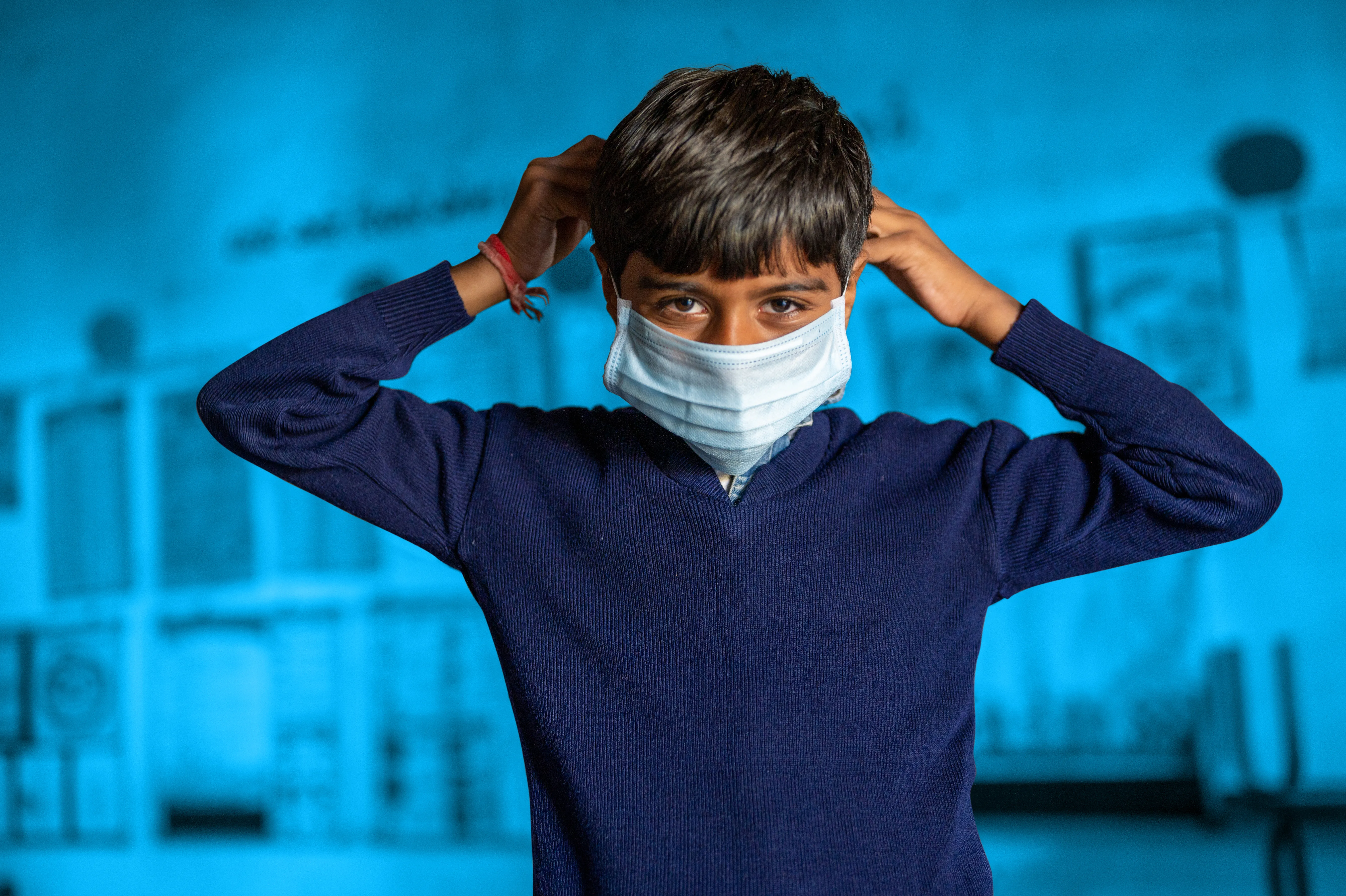 Young boy in blue wearing a facemask