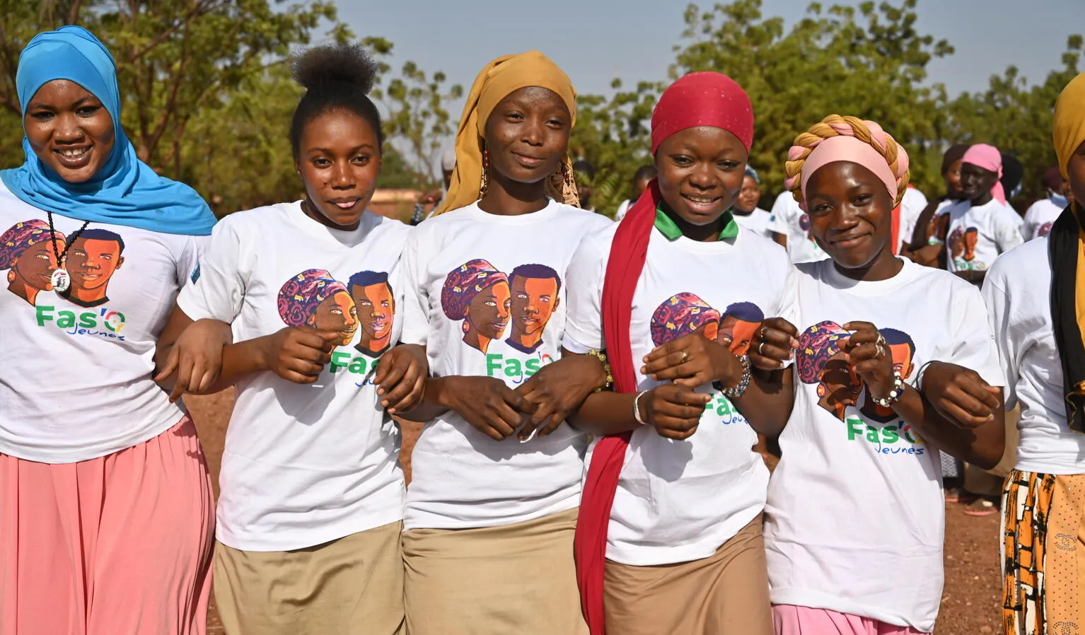5 young girls stand with arms locked, looking at the camera in Ouahigouya, in the North of Burkina Faso.