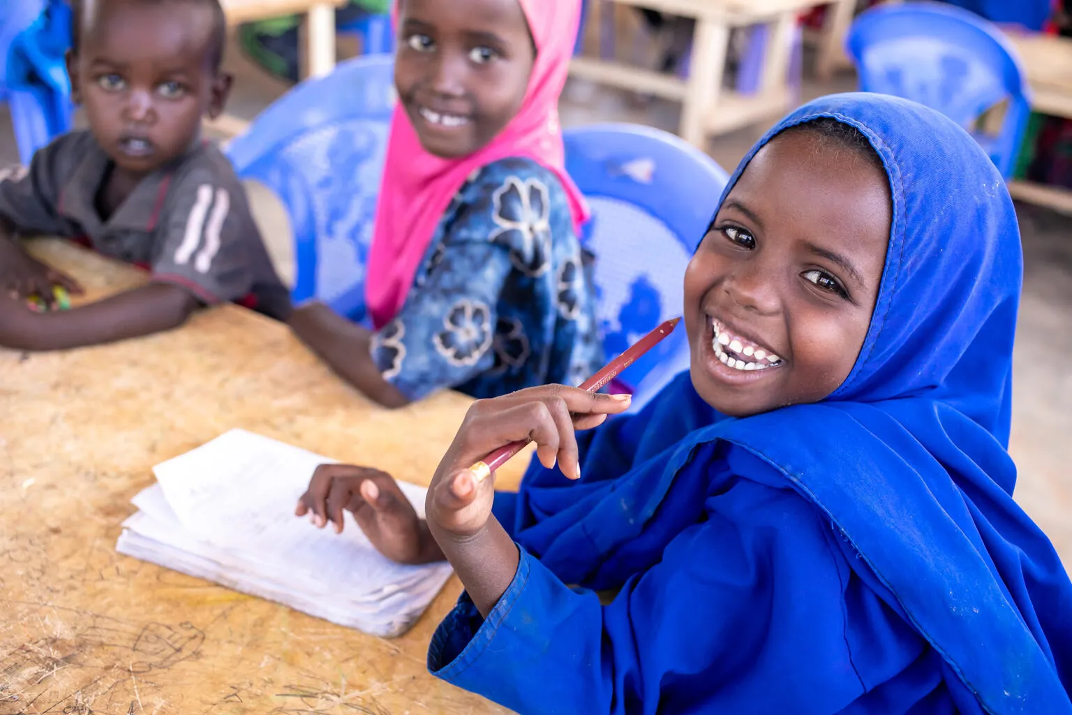 Young students laugh while doing school work together at a table in a primary-school classroom in Dolow, Somalia.