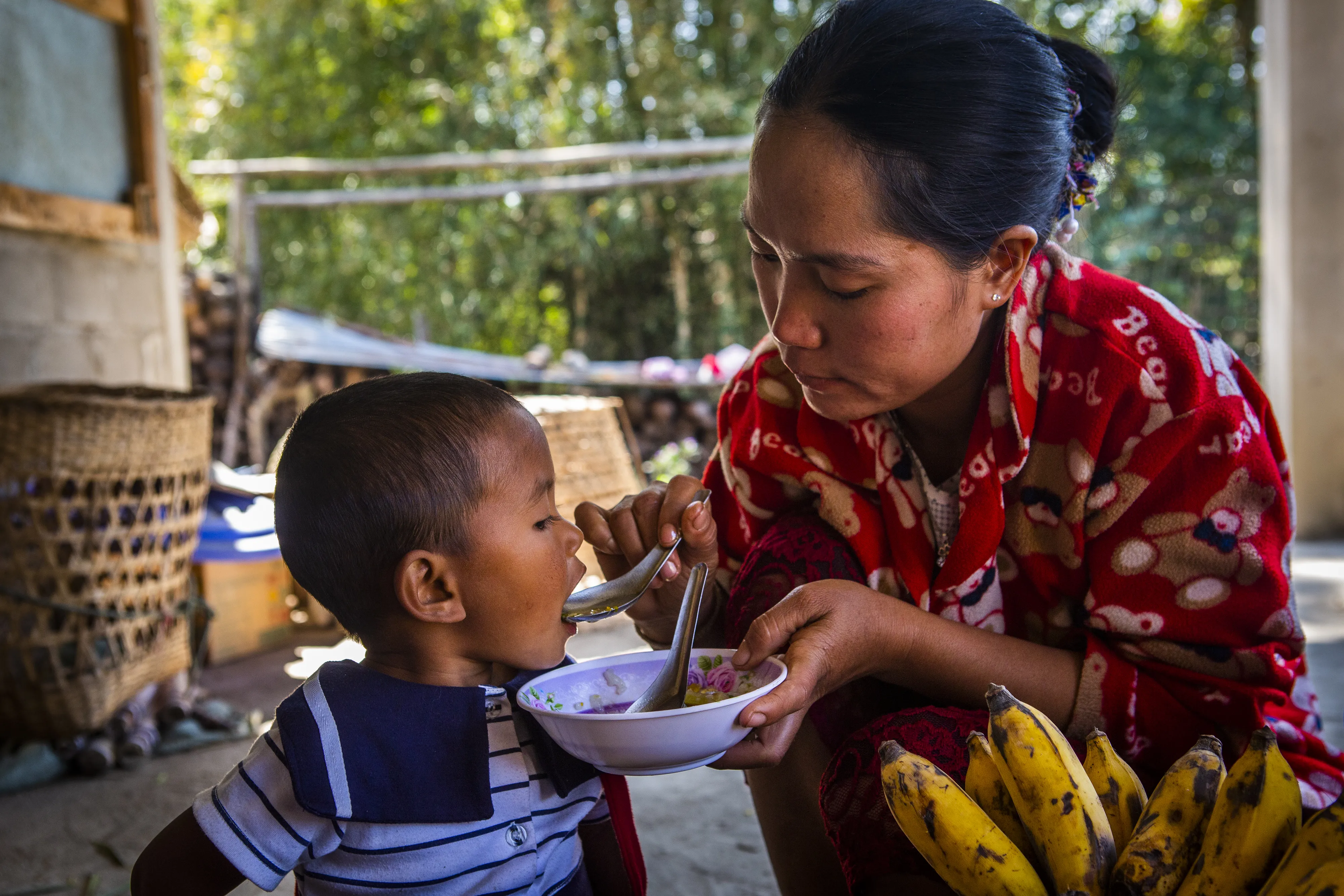 Daw Buu Shane feeding her daughter a nutritous meal cooked with ingredients grown in her backyard. 
