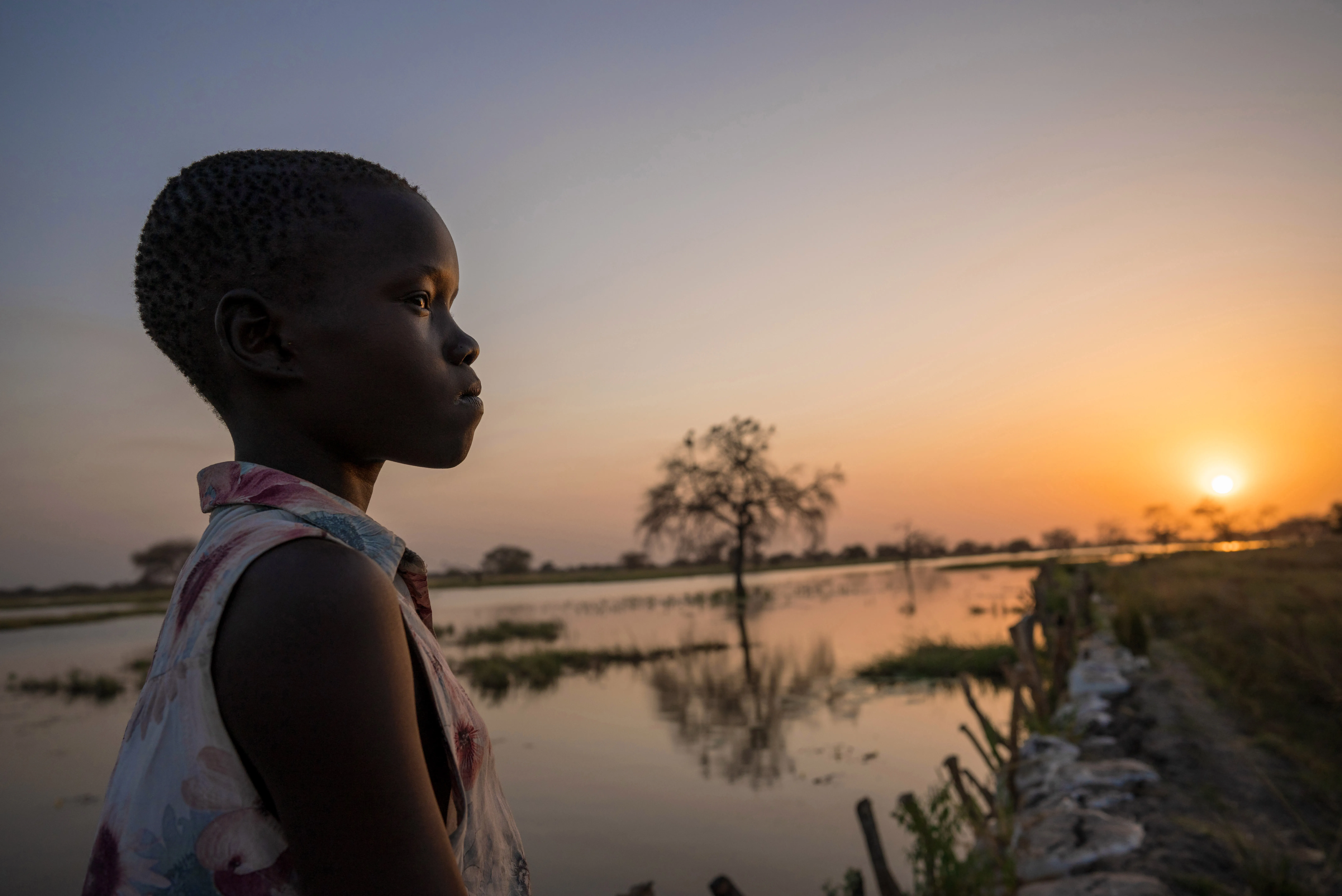 13 year old Ayak Anhiany Lual walks past flooded water outside the village of Panyagor in Twic East, Jonglei State in South Sudan.