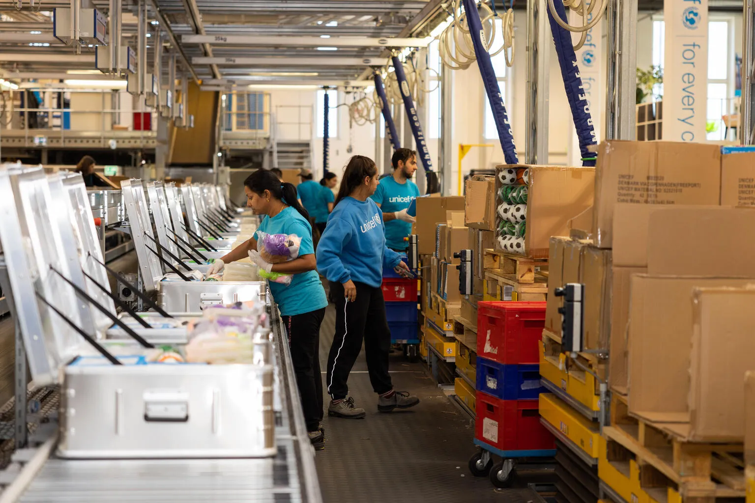 UNICEF workers and volunteers pack boxes for shipping. 
