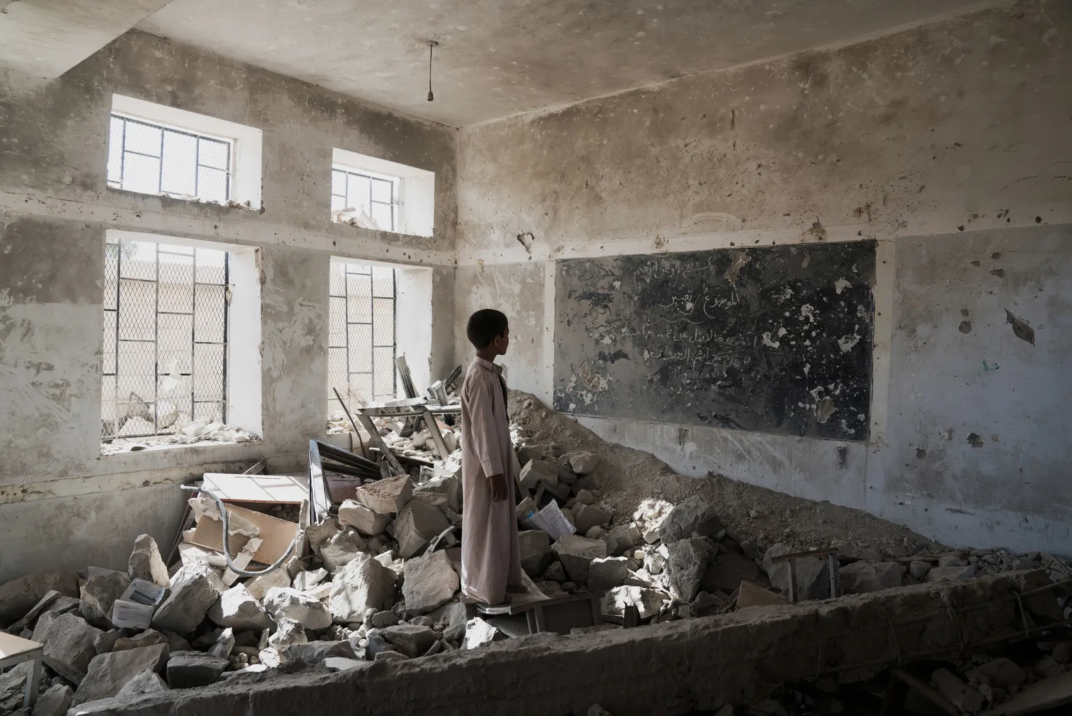 A student stands in the ruins of one of his former classrooms