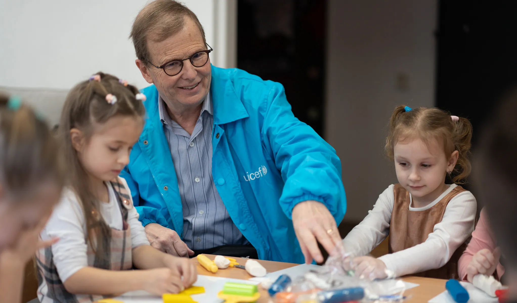 David Morley interacting with children sitting at child's table. 