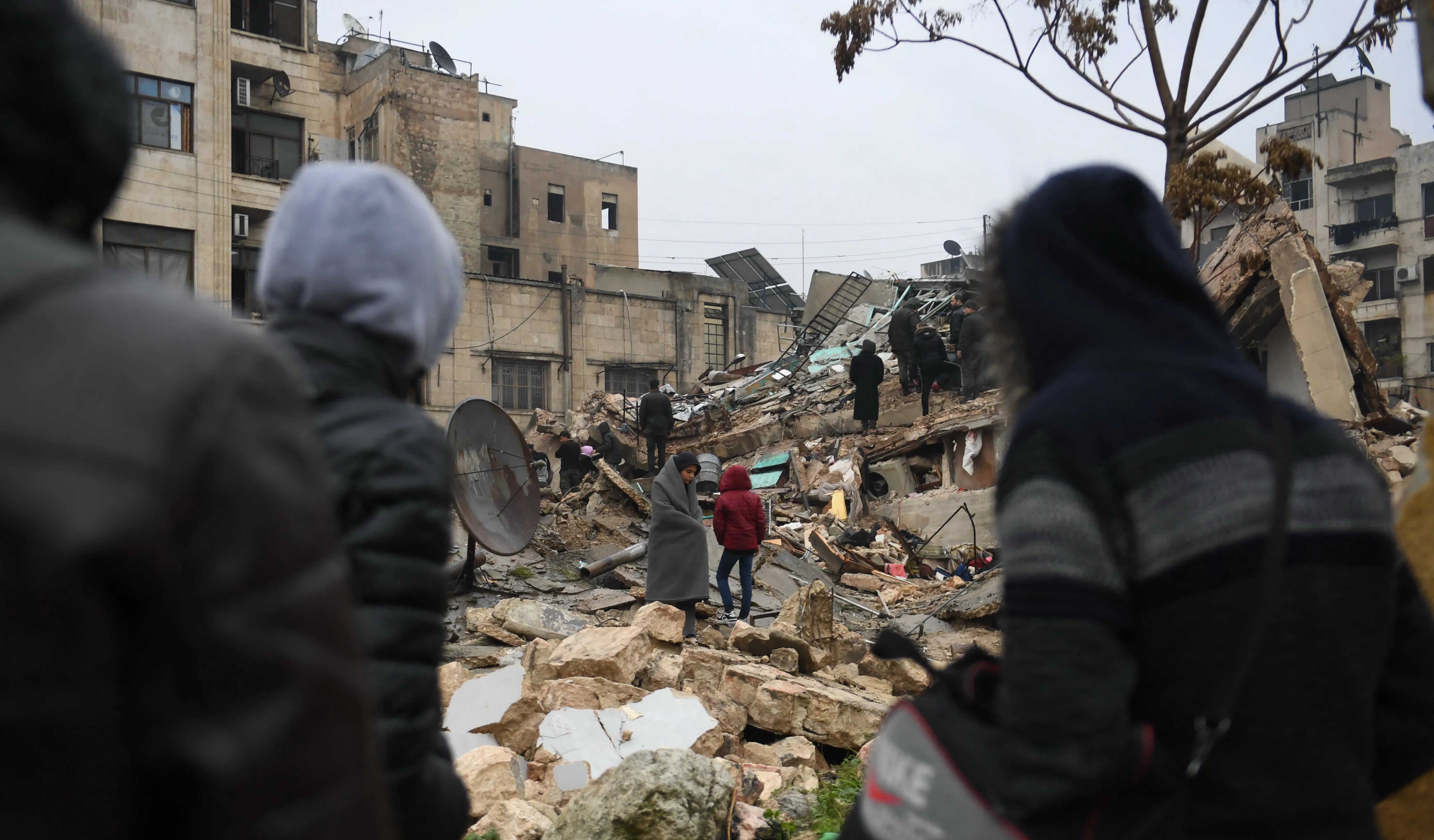 On 6 February 2023, people gather around collapsed buildings as rescue teams look for survivors following an earthquake in the government-held Syrian city of Aleppo. 