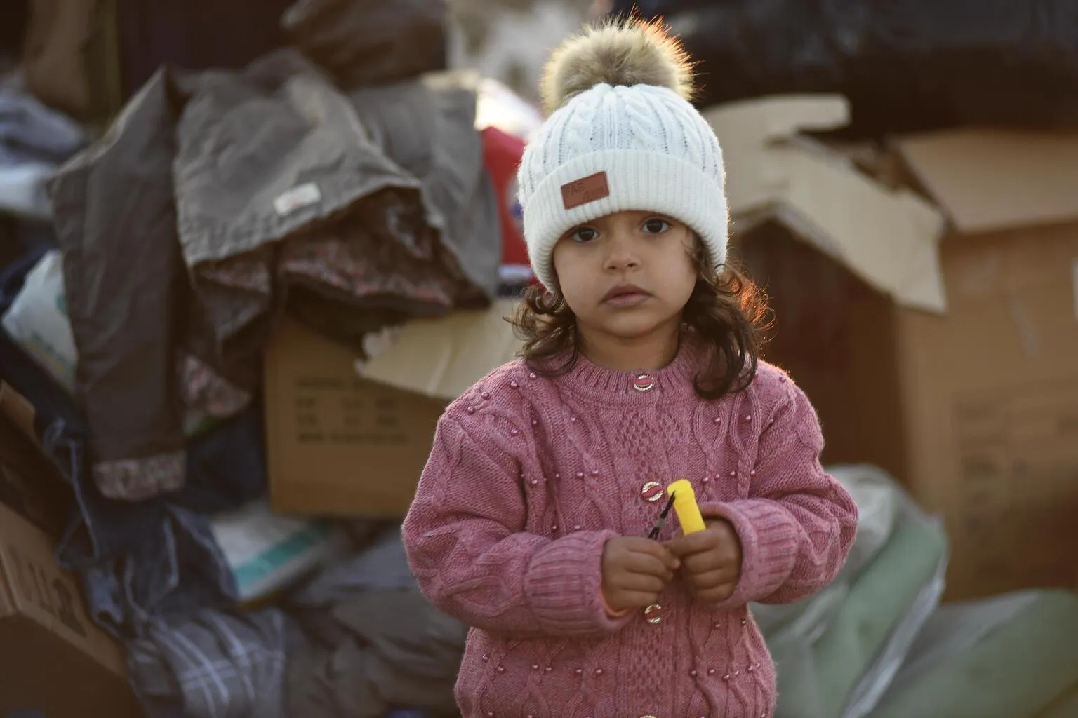 A little girl stands amongst the boxes of supplies sent to the survivors of the 7.7 magnitude earthquake in Kahramanmaraş, Türkiye.