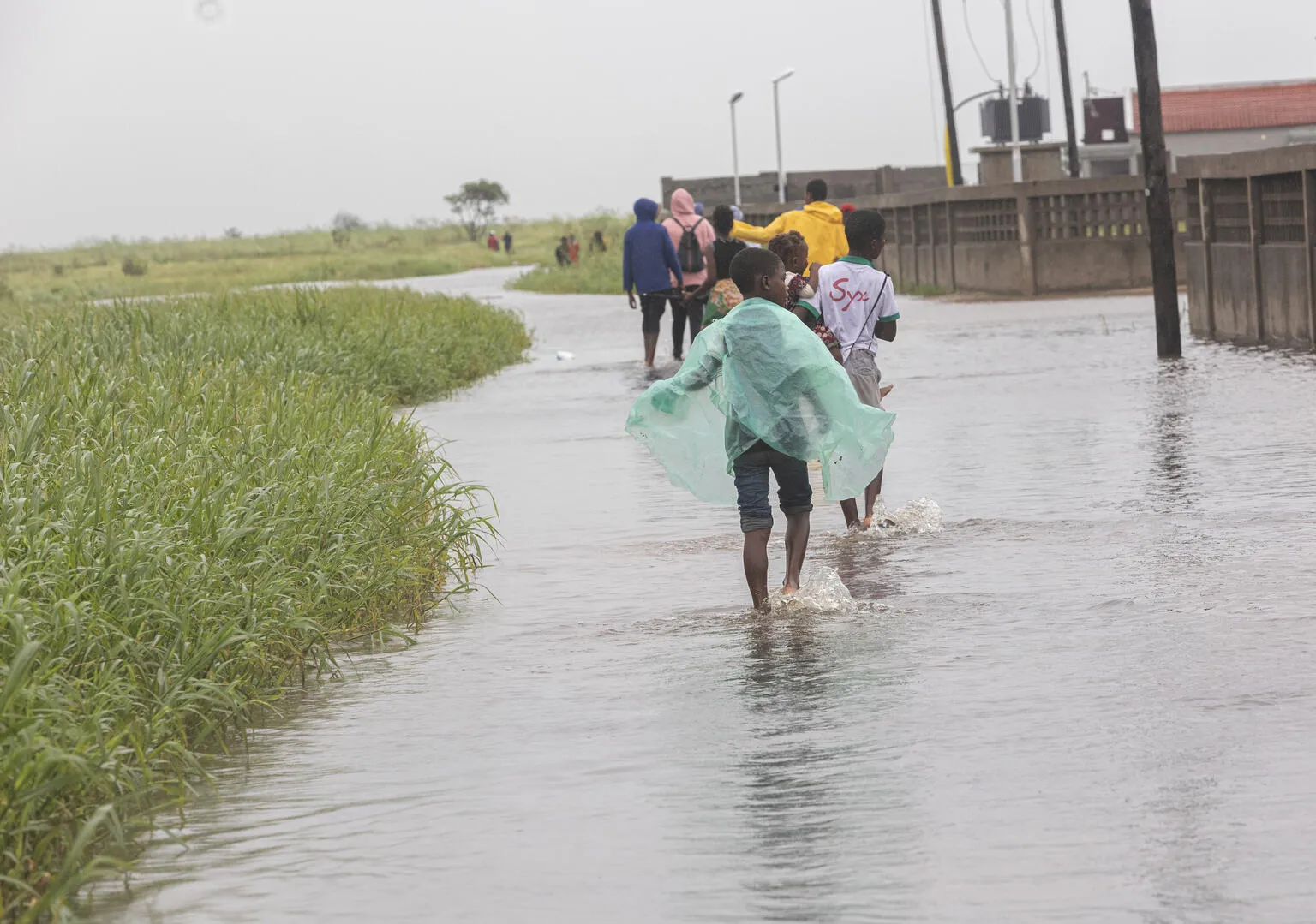 March 13, 2023. A group of children walks through a flooded street after Cyclone Freddy passes through Quelimane on March 11.