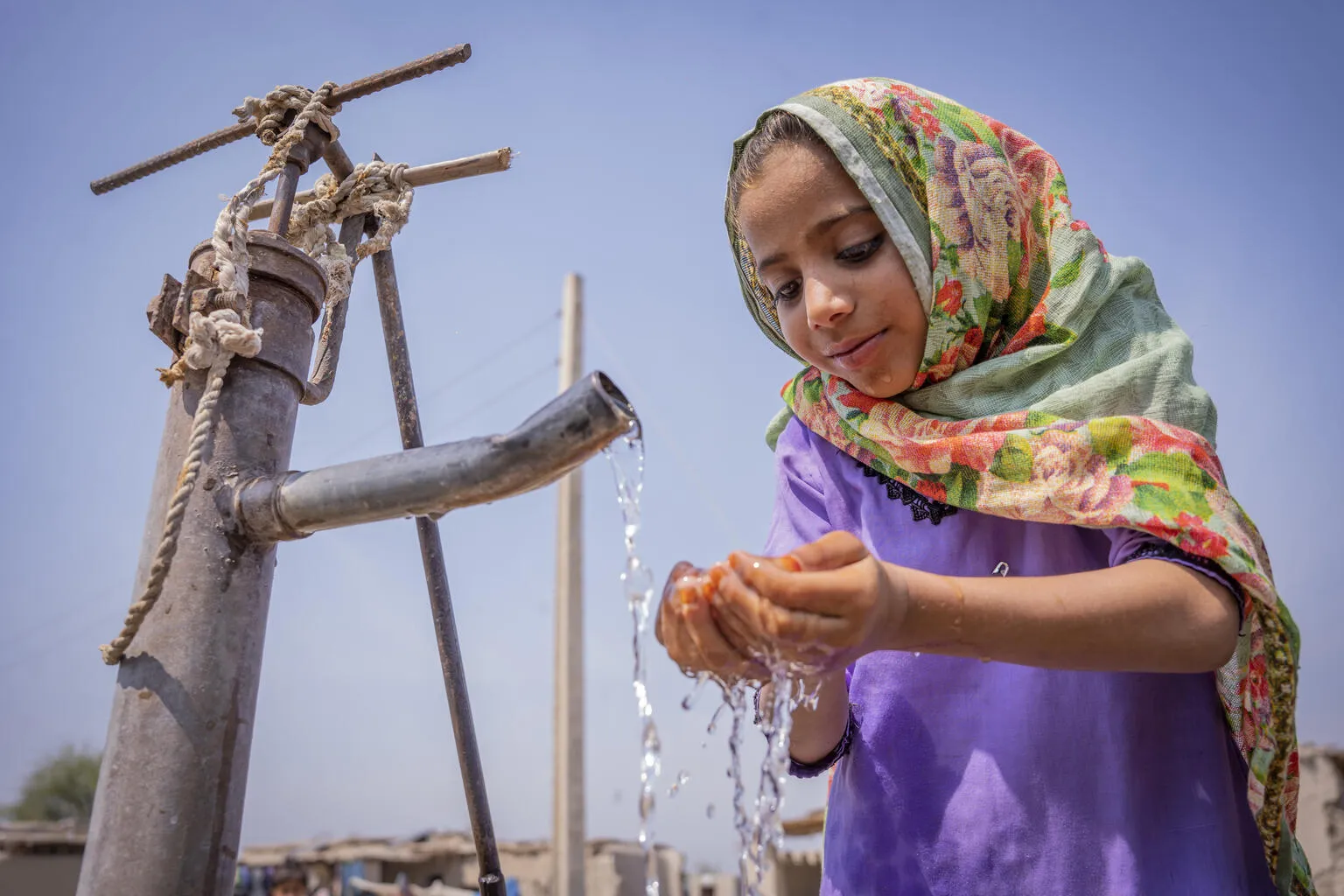Nafisa (6) drinking water from a community handpump.