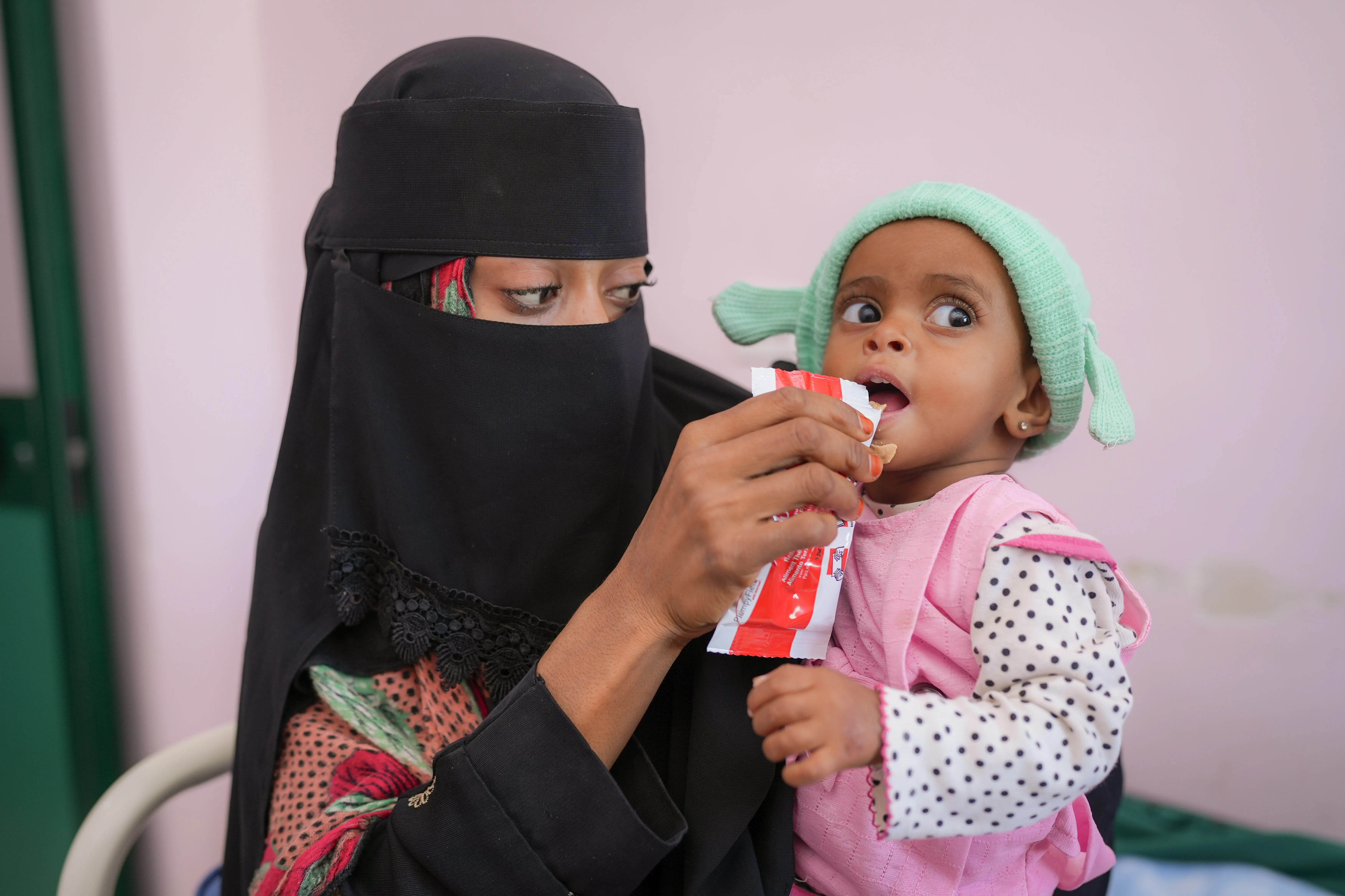 On 23 February 2023 in Aden, Yemen, 16-month-old Rowaida Raeed Ali Hasan is fed a sachet of Plumpy ‘Nut ready-to-use therapeutic food (RUTF) by her mother, Gouma’a Mohammed Hasan Abdullah. Rowaida is being treated for severe acute malnutrition in the Therapeutic Feeding Centre at Al Sadaqa Hospital.