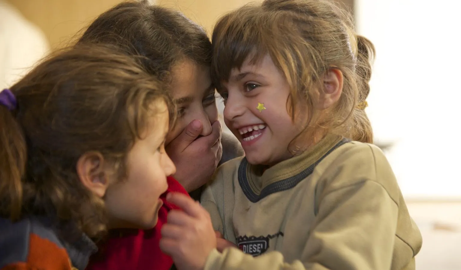 Safa (right) laughs with her twin sister and older sister.