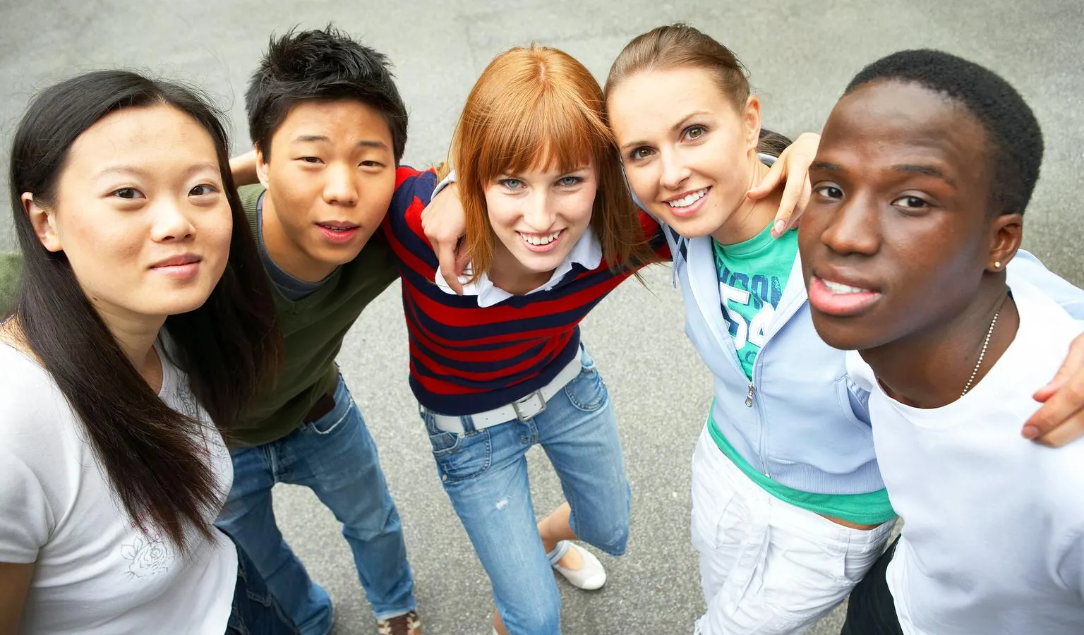 Five young people of diverse ethnic backgrounds look upwards smiling