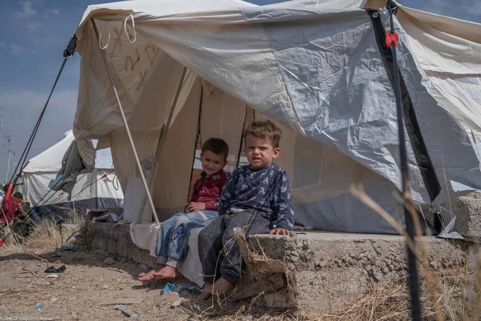 Syrian child sit outside a makeshift tent in Iraq