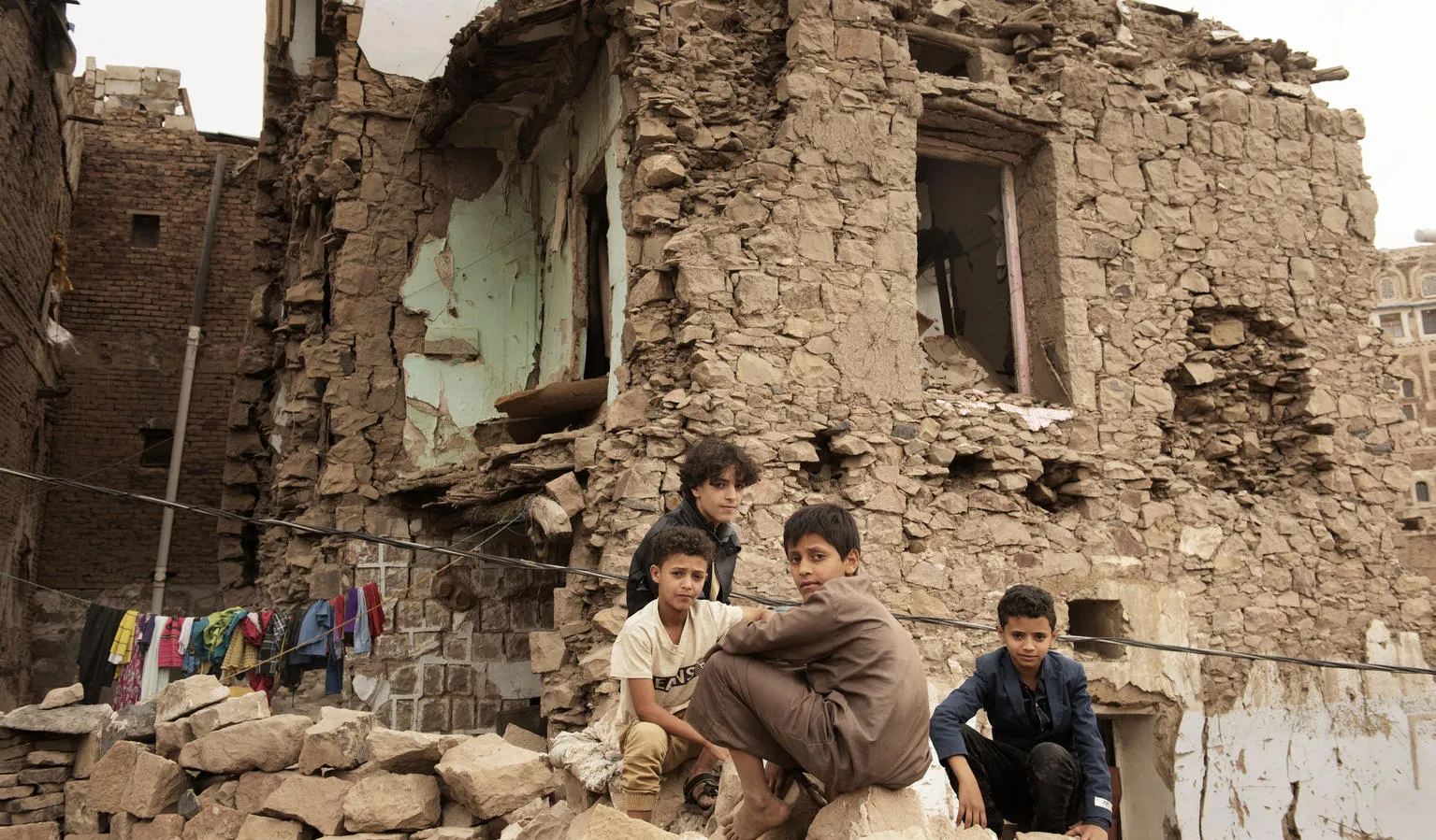 Boys sit in front of a bombed house in Sana'a Yemen