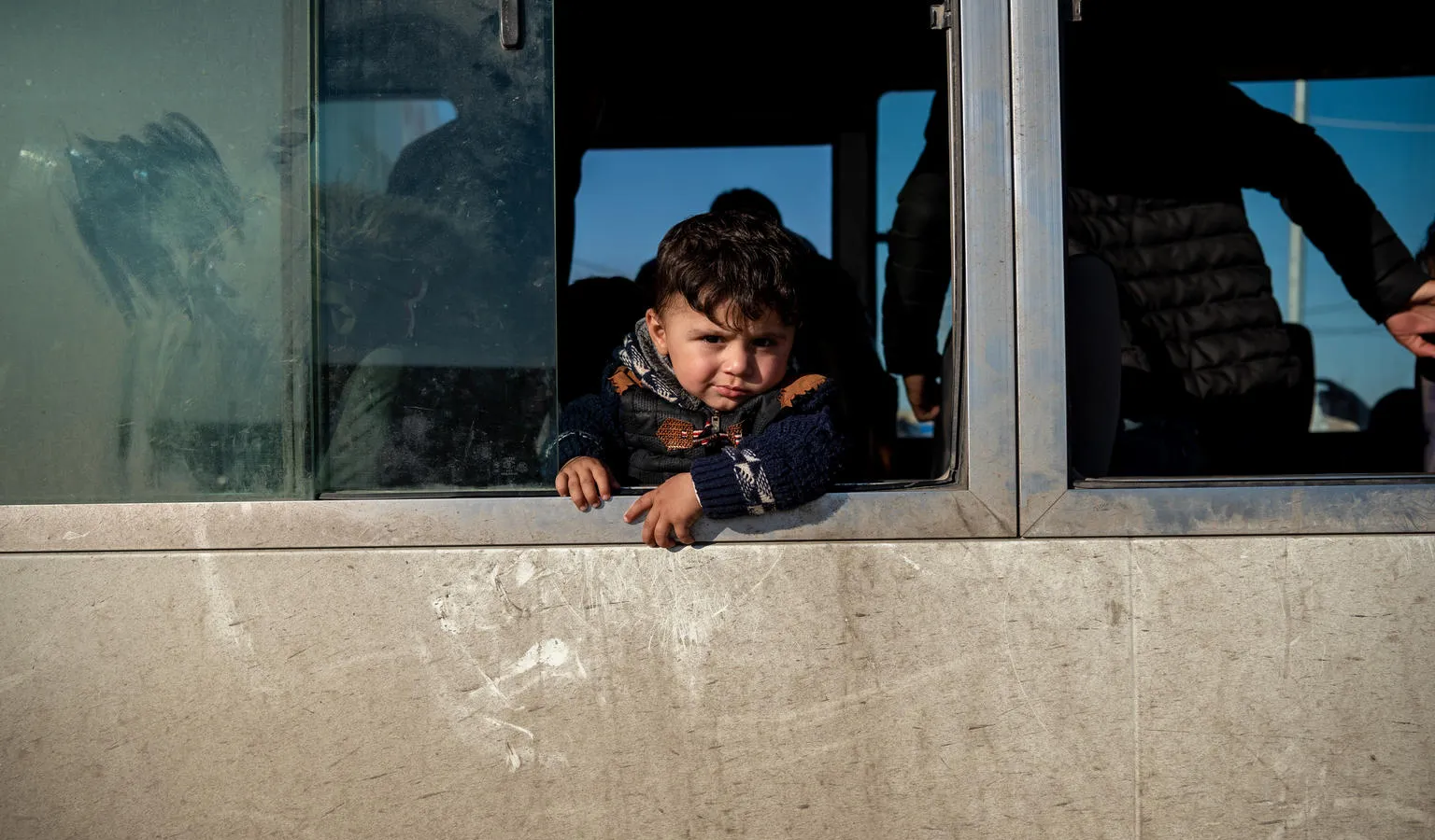 A child looks out a bus window at a temporary camp for Syrian refugees in Iraq.