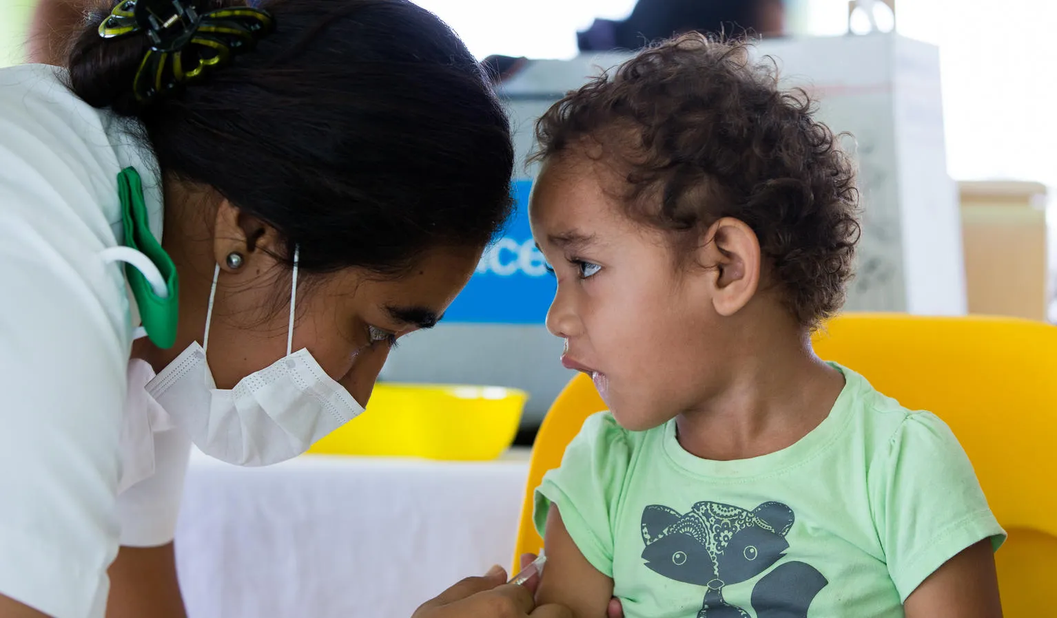 A little boy watches a nurse as he receives a vaccine shot.