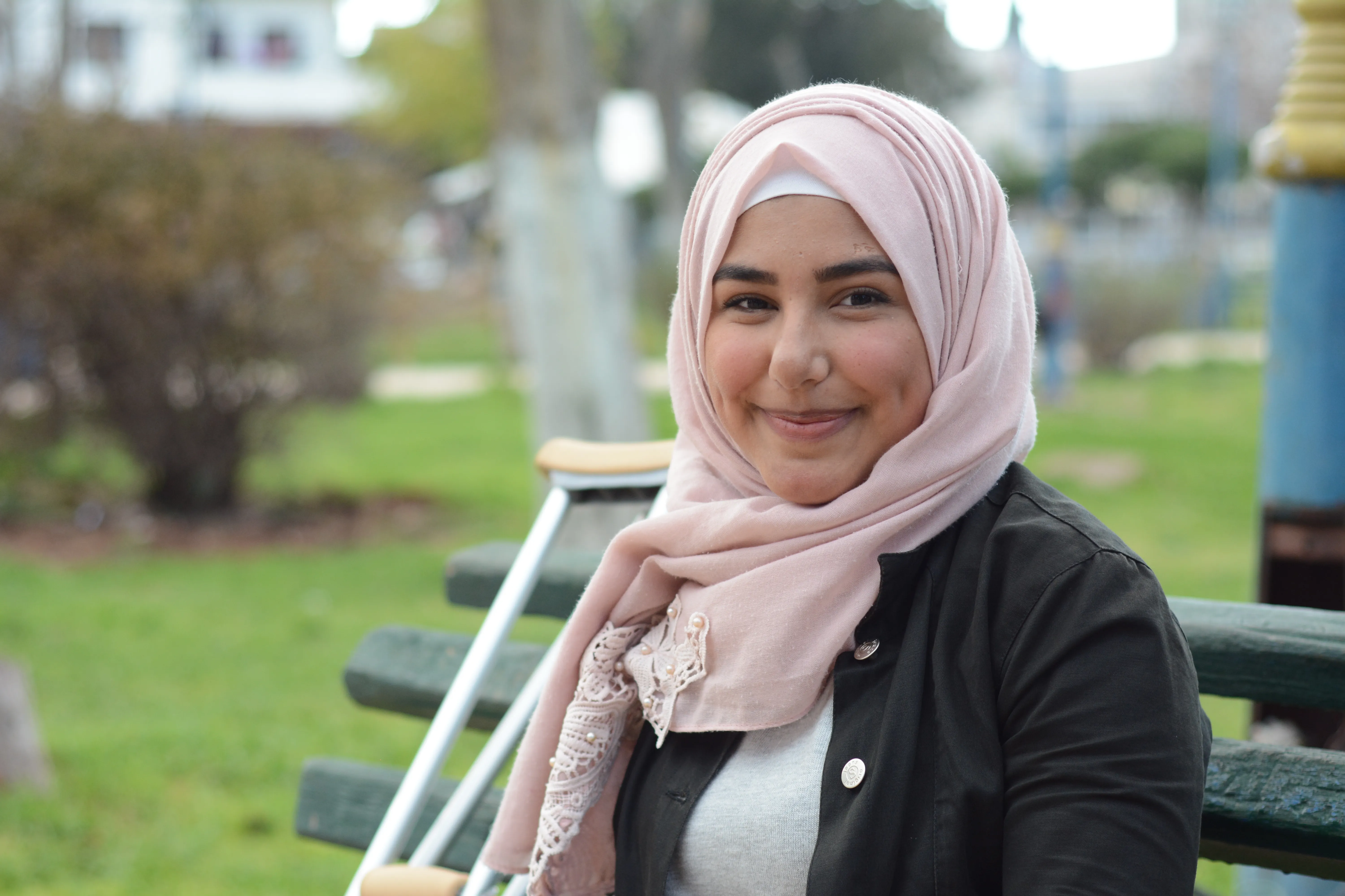 Nour sitting on a bench with her crutches beside her.