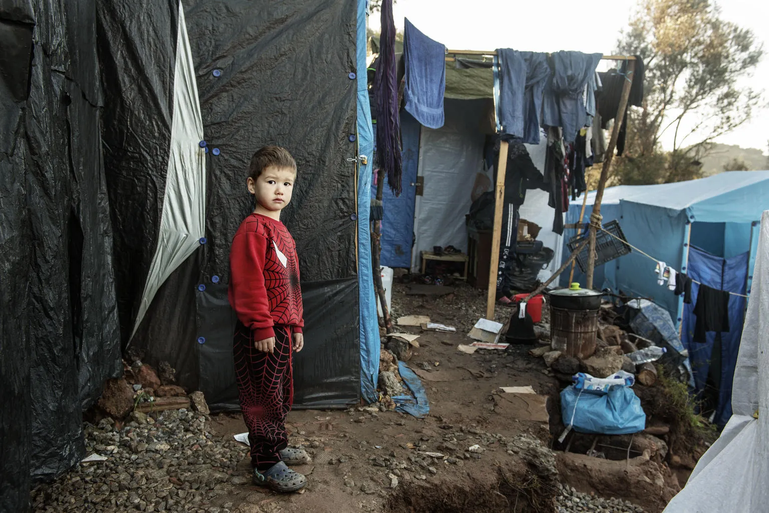 A boy stands in a makeshift camp for refugees.