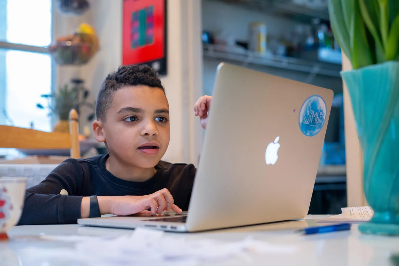 Boy doing homework on laptop at kitchen table