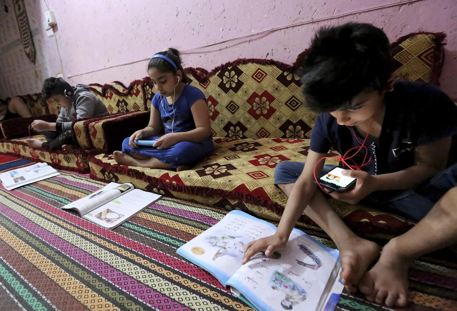 Children study using recorded lessons at a refugee camp.