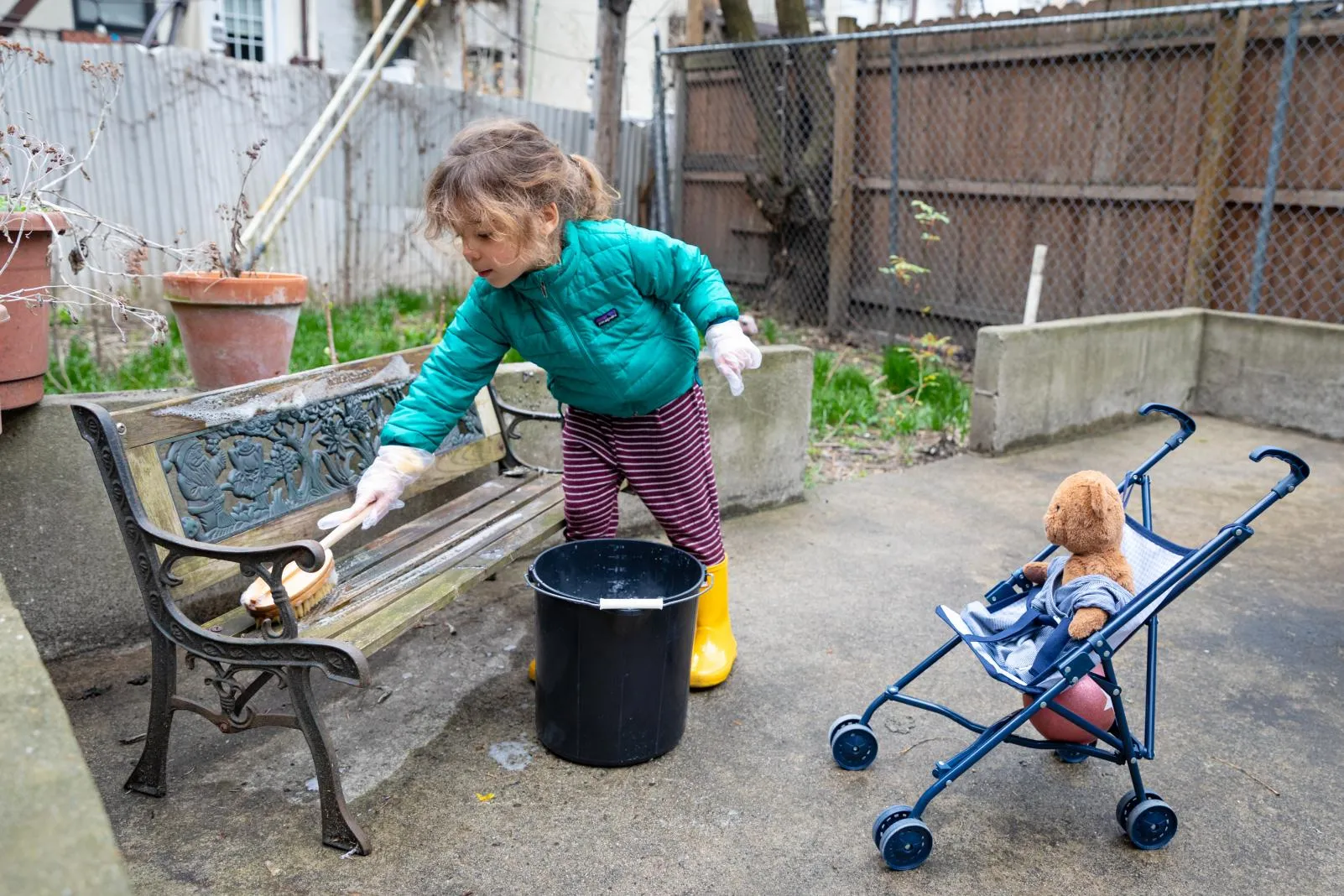 A little girl cleans her play area with soap and water.