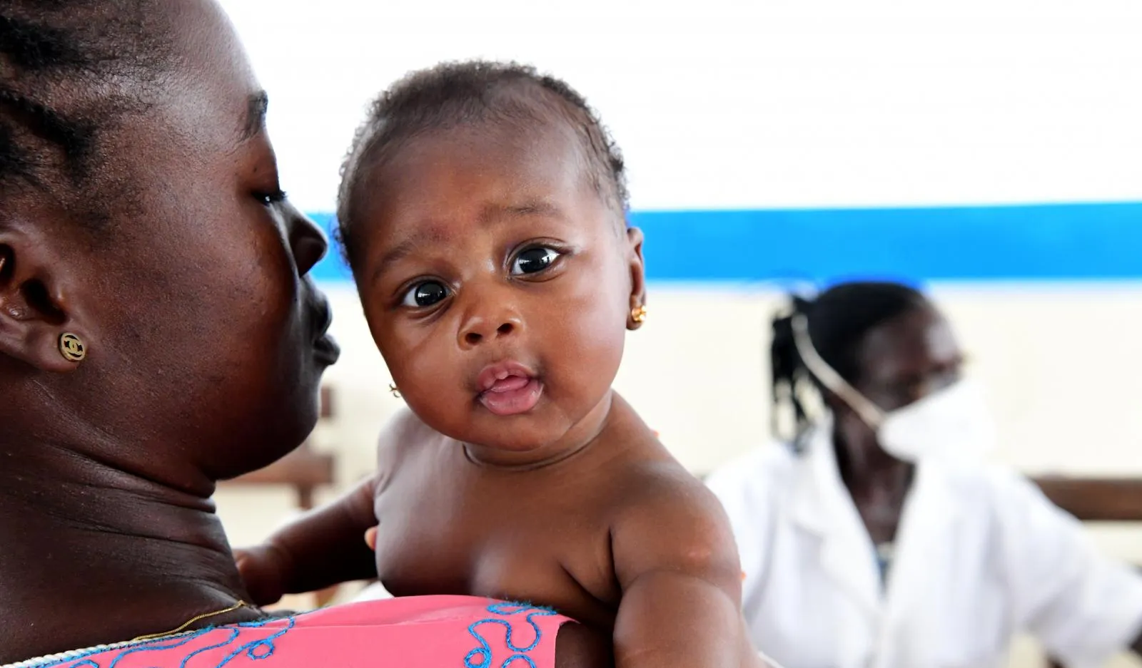 A mother holds her baby at a mobile clinic.