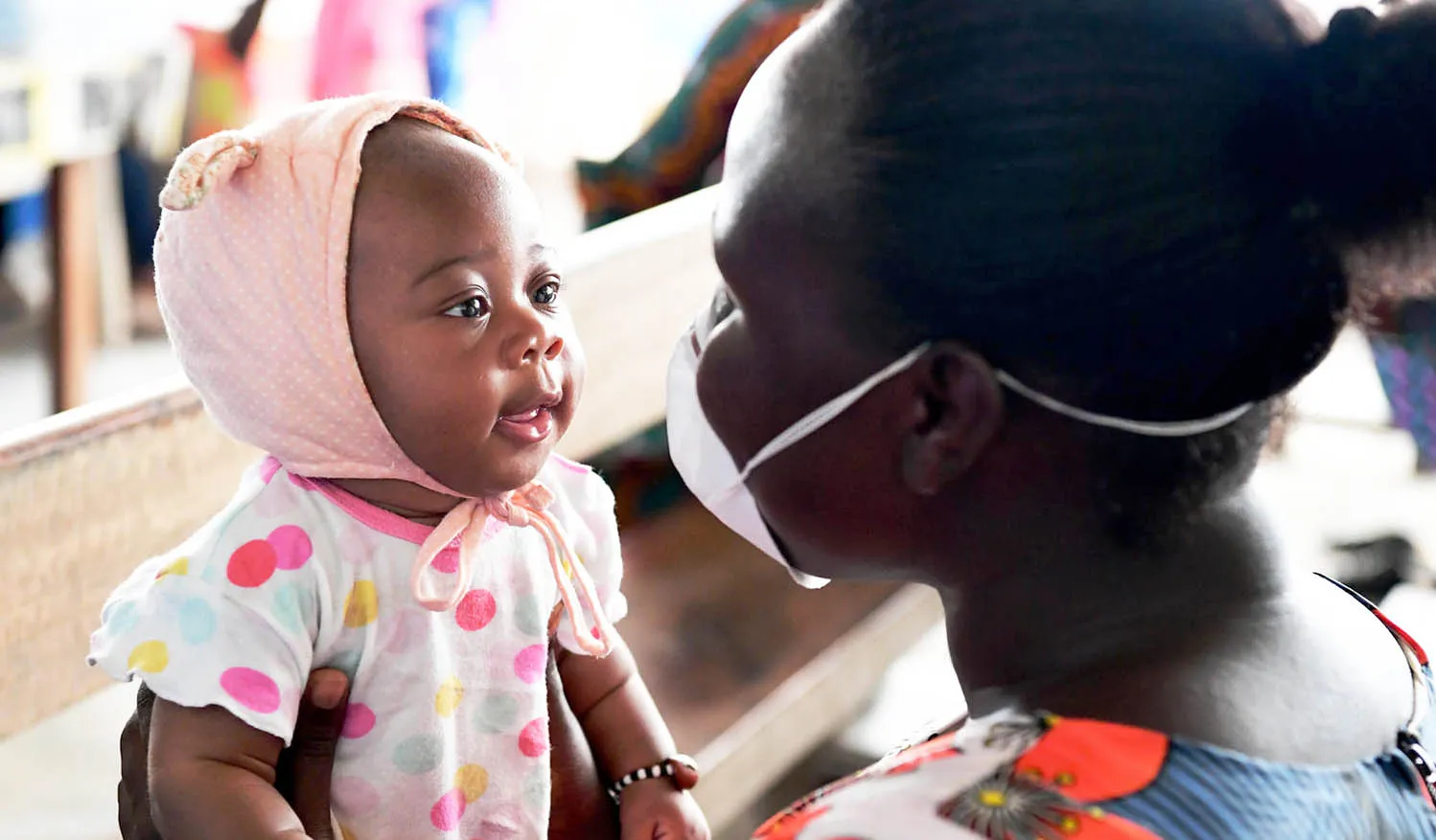 Amusée par le visage masqué de sa mère, Christelle, 3 mois, attend d’être vaccinée dans un centre de santé près d’Abidjan, en Côte d’Ivoire. 