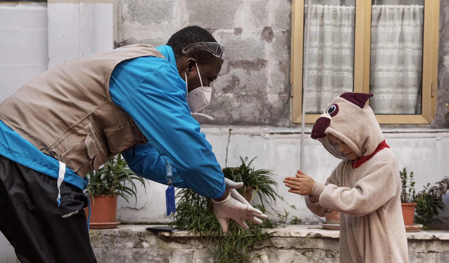 A UNICEF Italy staff member demonstrates handwashing to a young migrant girl.