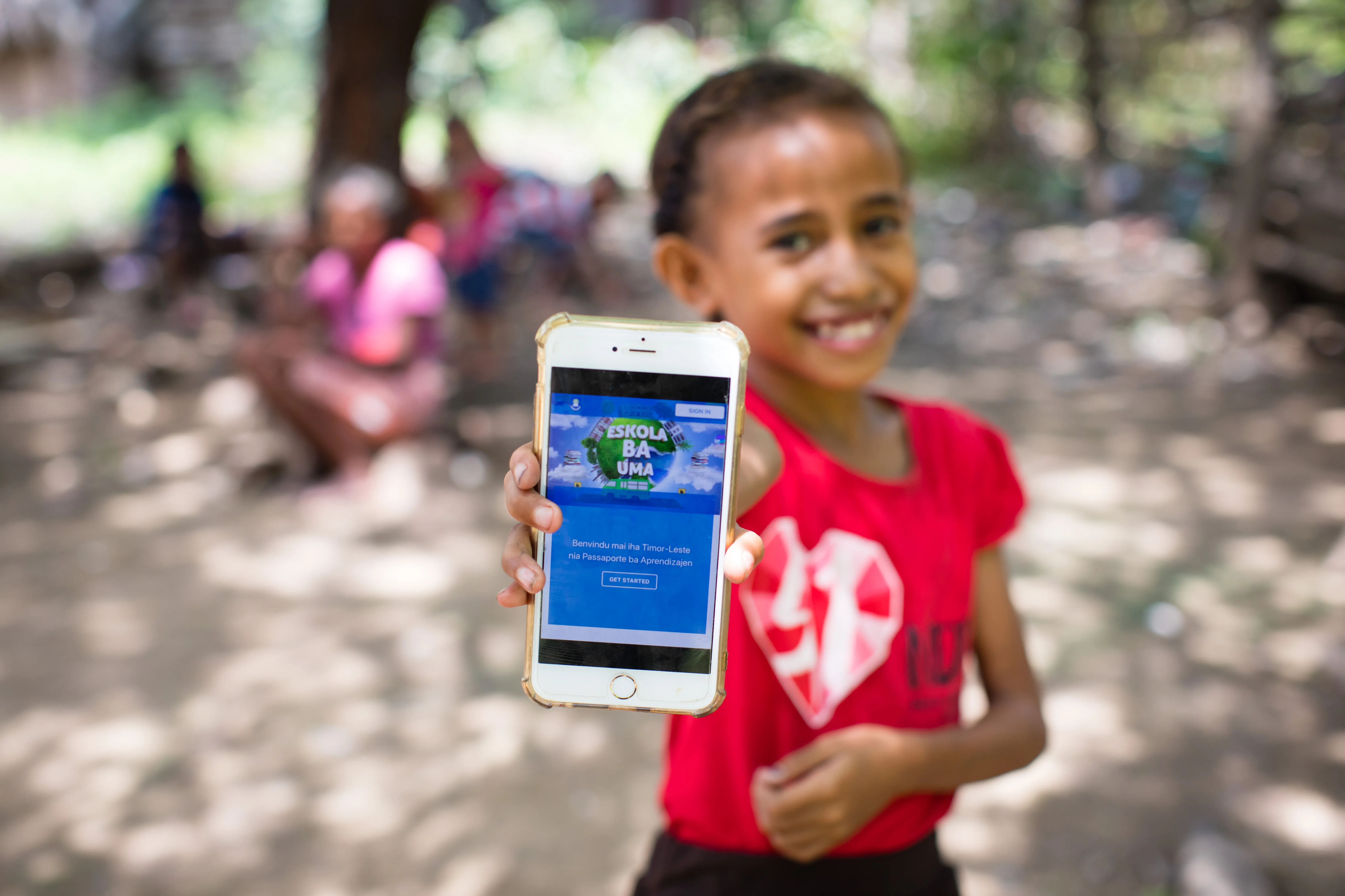 Child in Timor-Leste holding up cell phone with the Learning Passport on the display