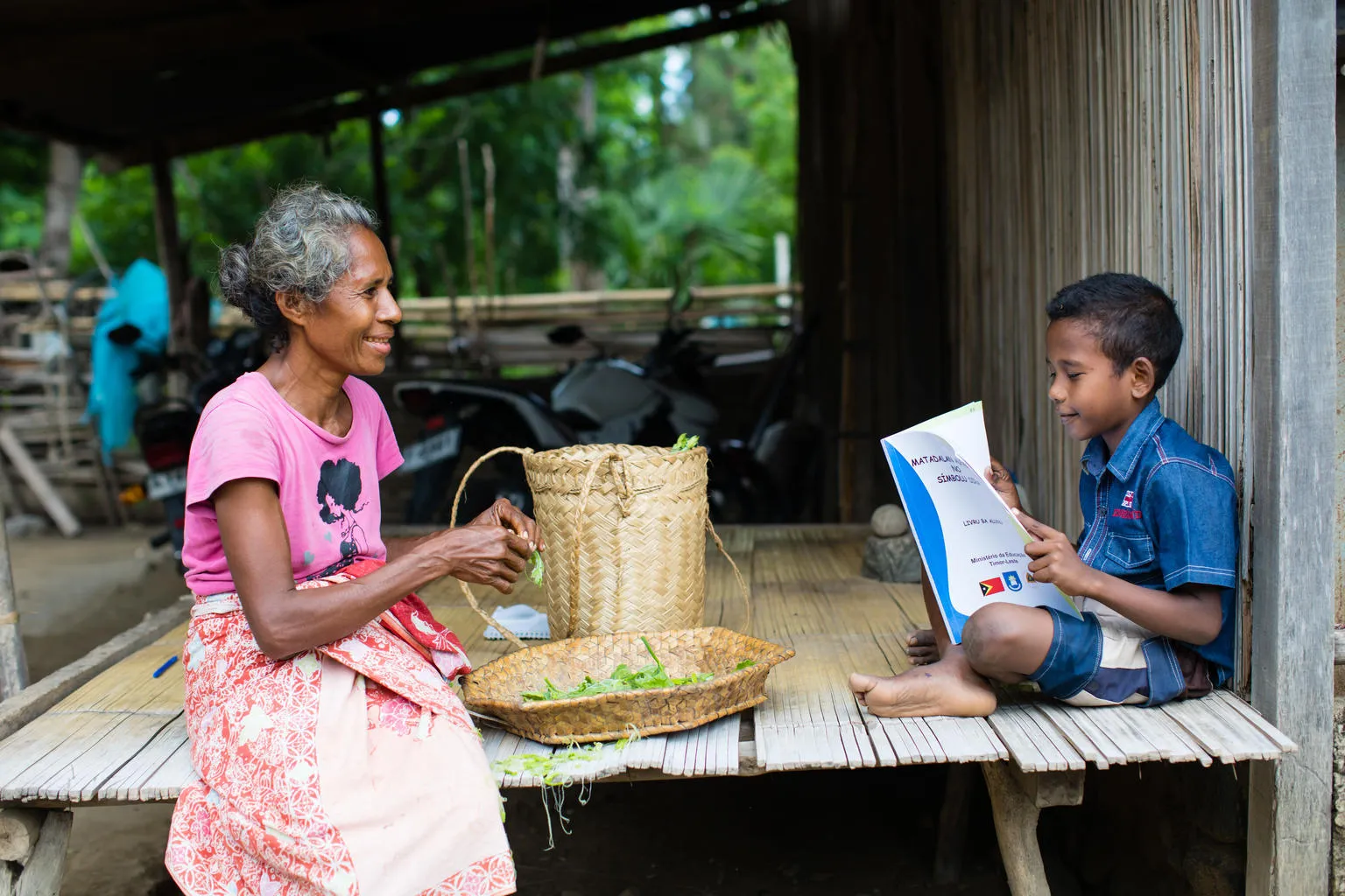 A boy reads to his grandmother in Dalli, Timor Leste.