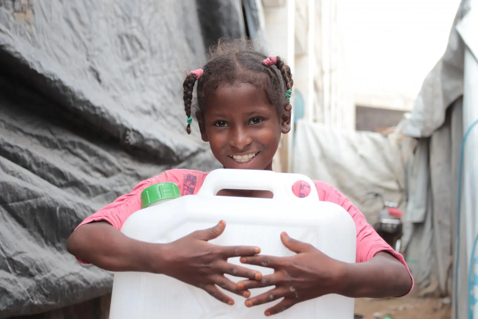 A little girl holds a jerry can of clean water.