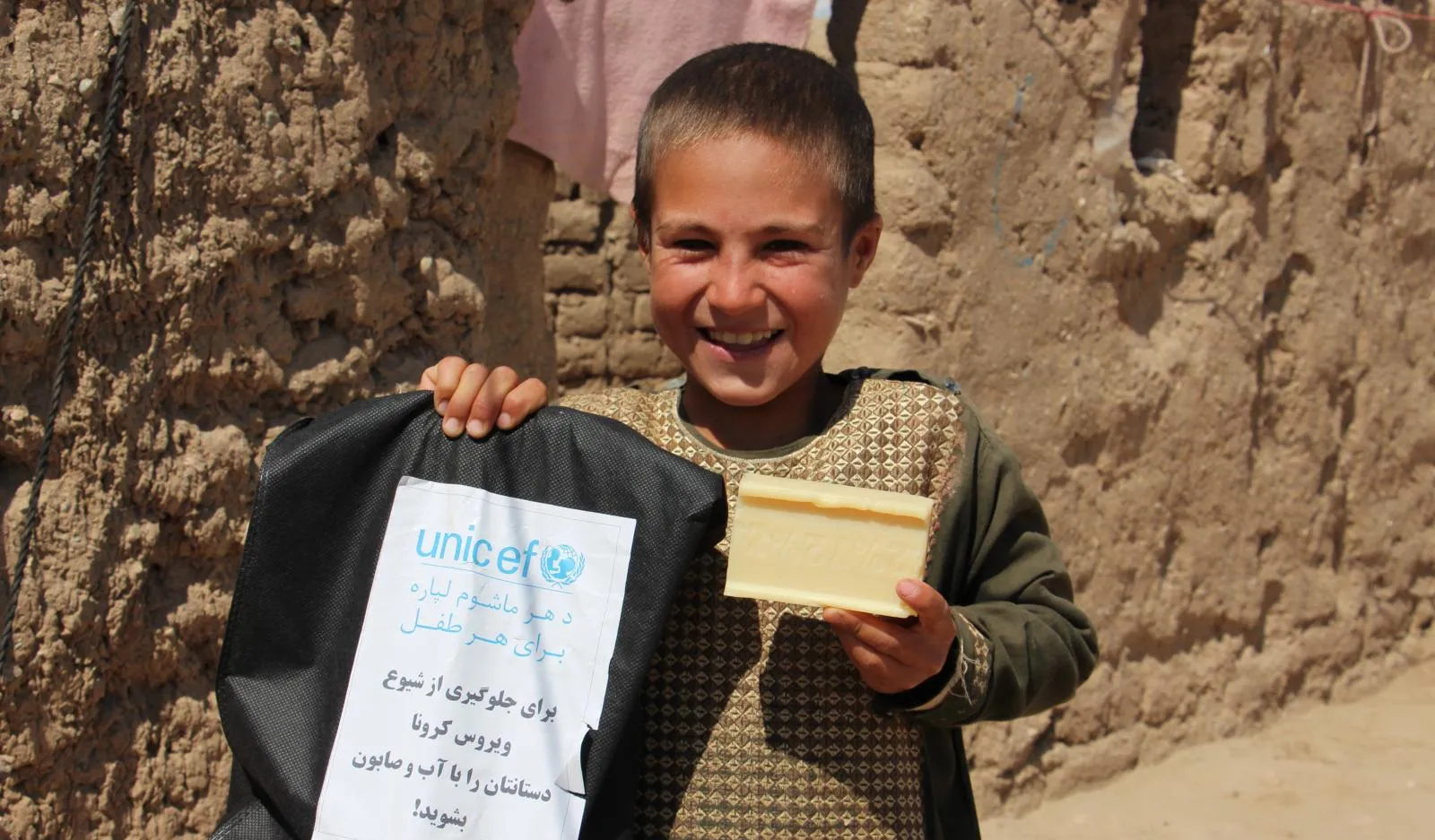 A boy shows off a bag of WASH supplies and a bar of soap.