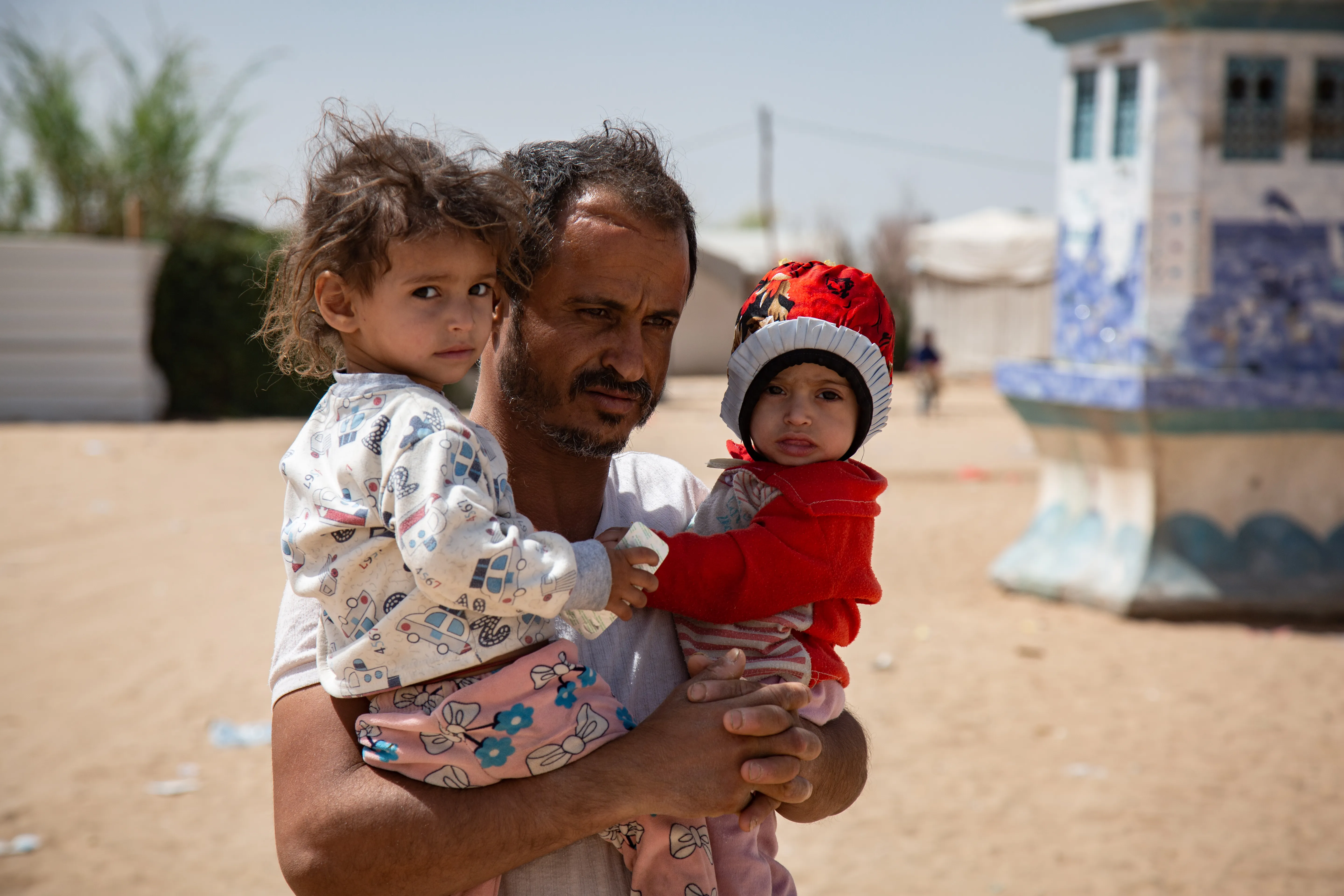 After receiving the food supplements for his 2 malnourished daughter, Moharram Al-Oshari is taking his daughters, Bulqis and Arwa back to their tent.