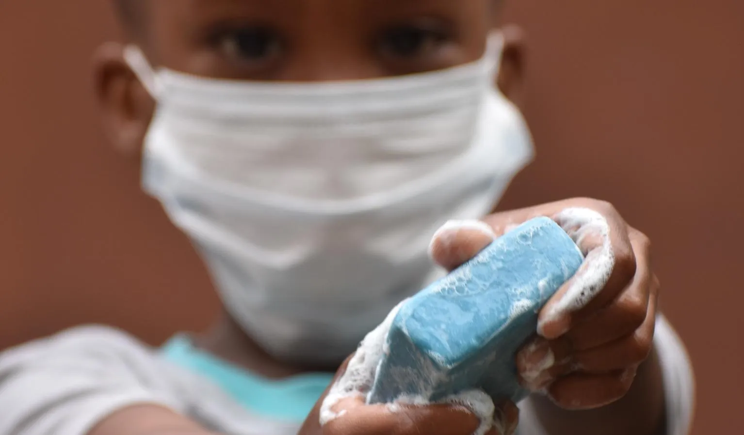 A little boy holds up a bar of soap.