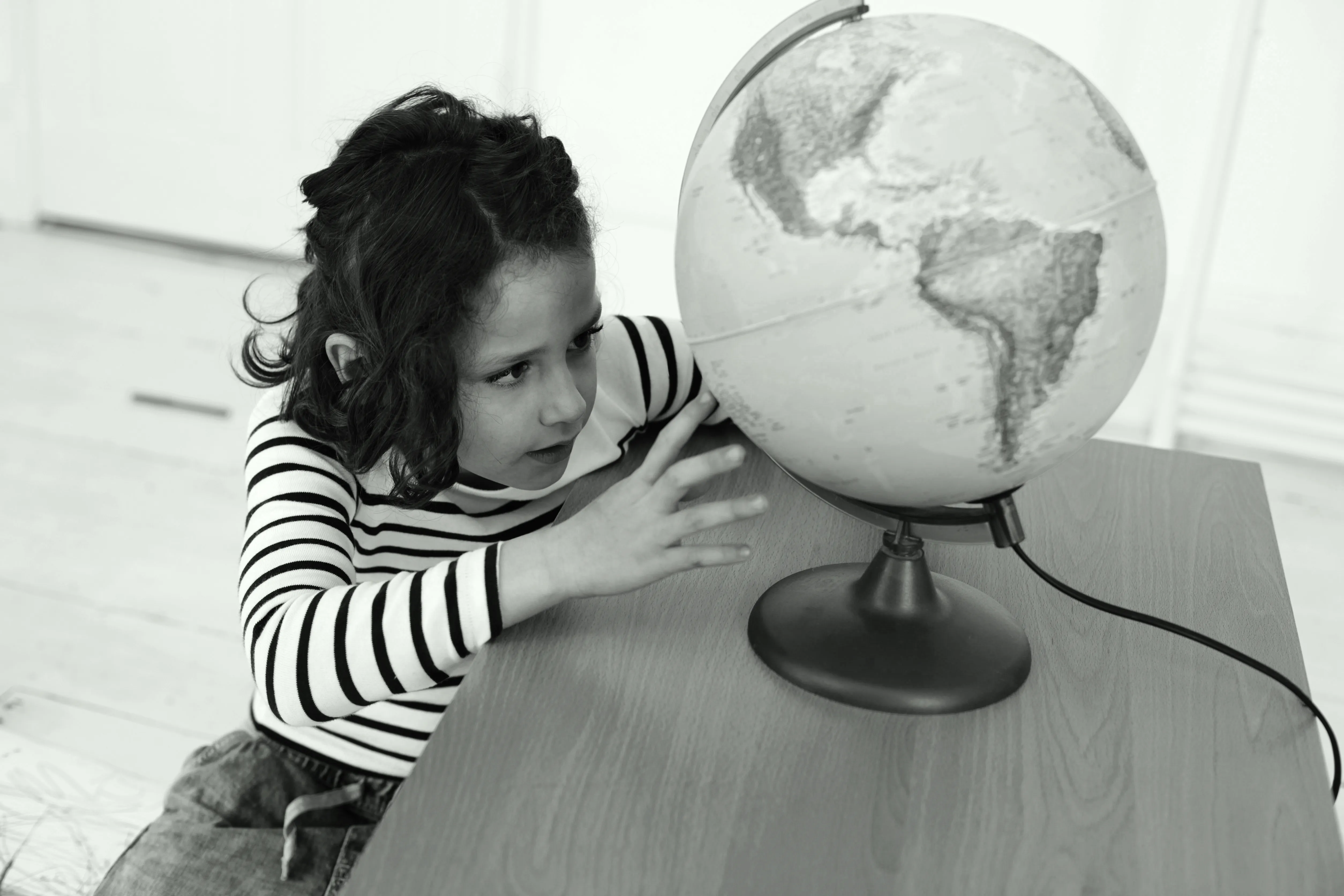 Young girl looking at a globe on a desk