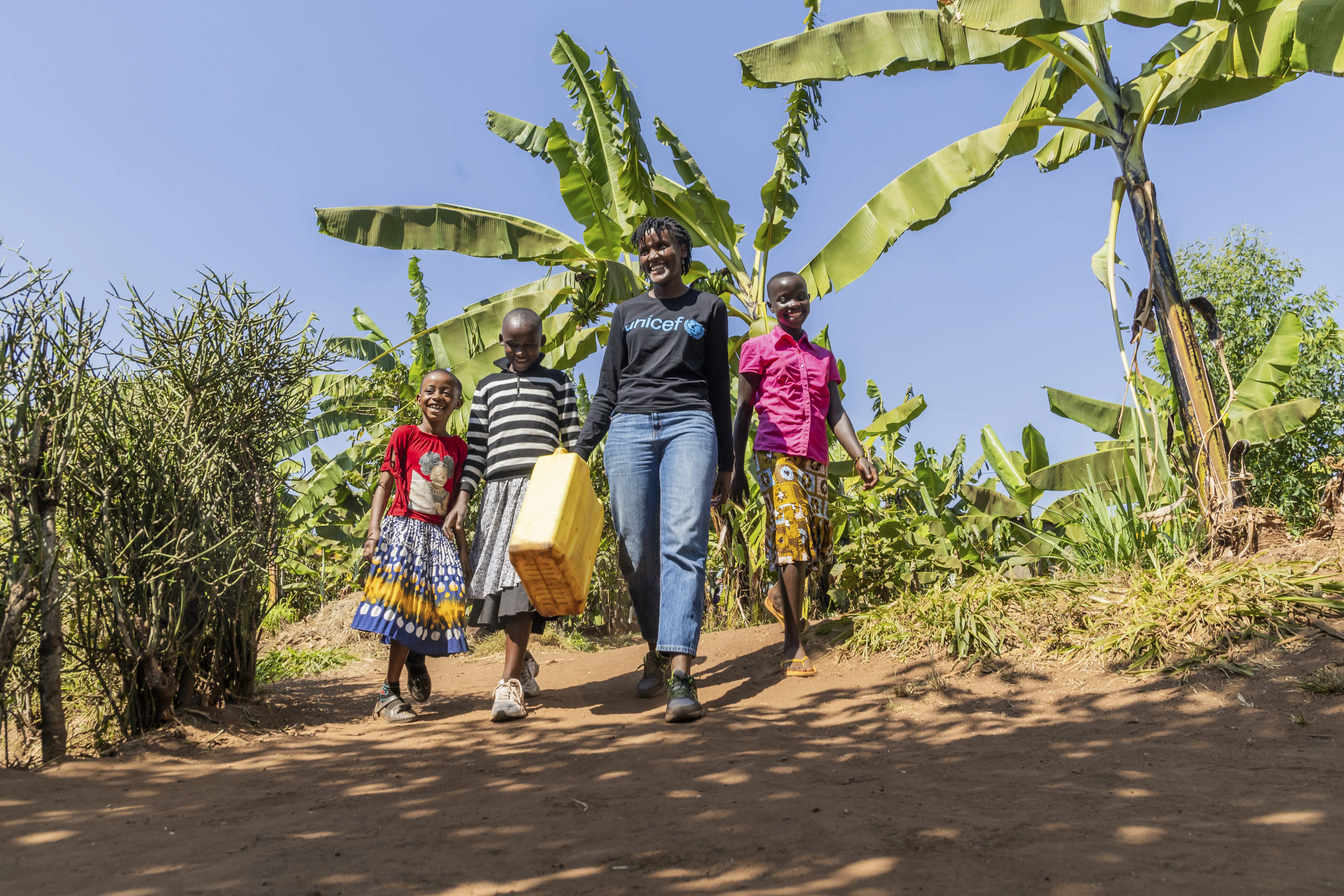 On 17 July 2023, UNICEF Goodwill Ambasador Vanessa Nakate walks with Adele (in pink), Graciella (in black and white stripes) and Bonette in Kigarama Sector, Kirehe District, Eastern Province of Rwanda.