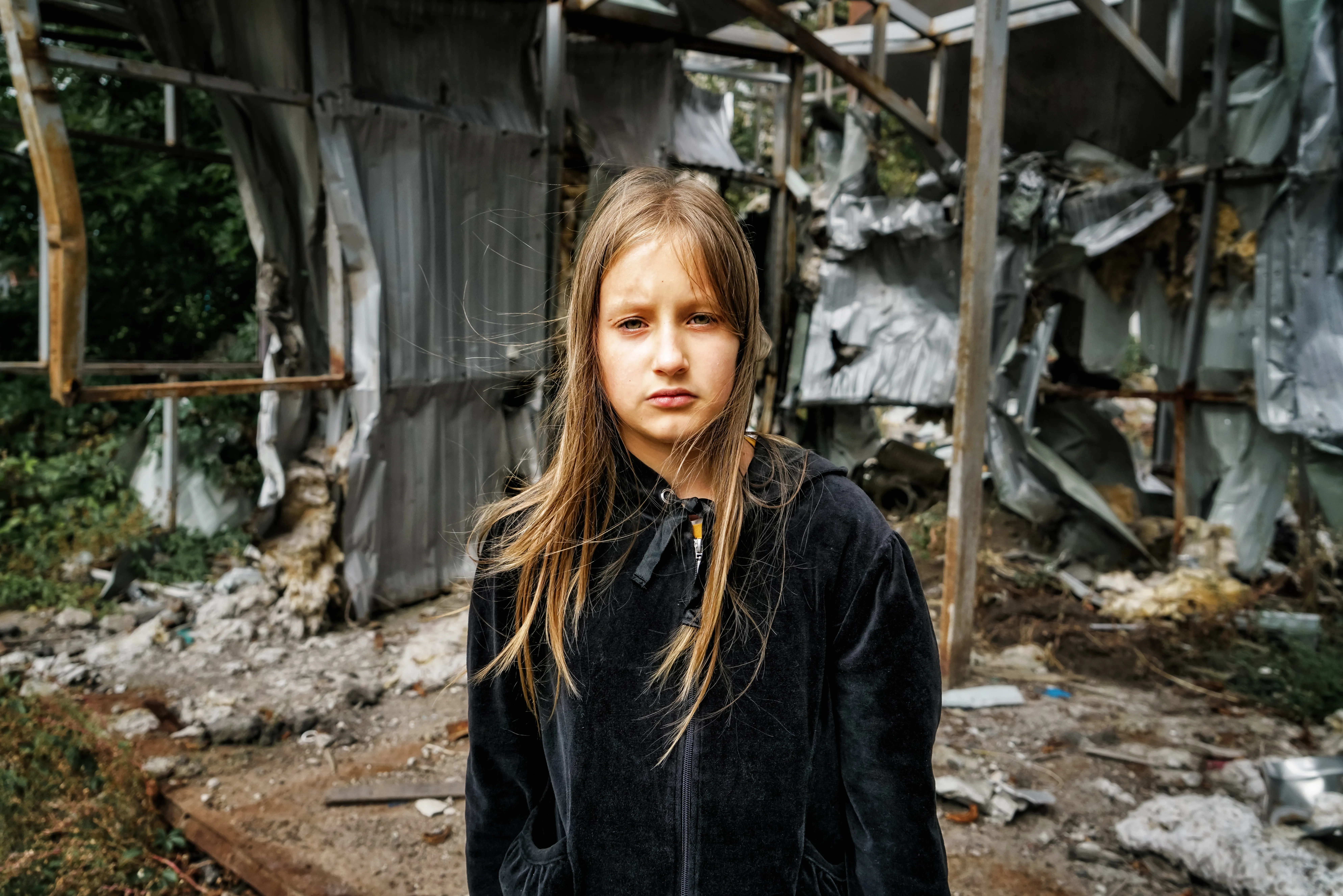 Arina, 10, stands on the spot where a shop used to be – right next to the children's playground in the village of Mala Rohan, in the Kharkiv region. Now it is a pile of rubble.