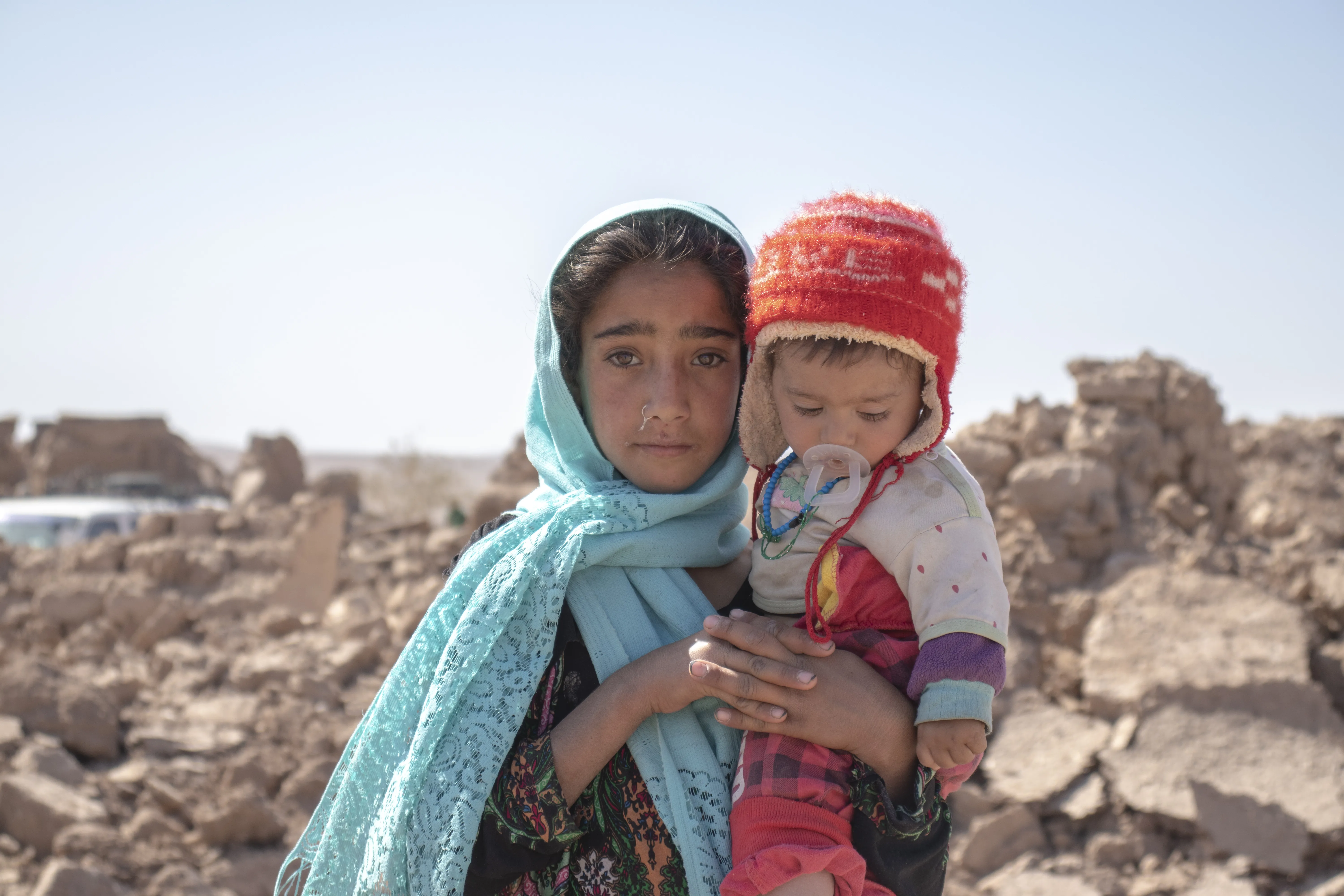 On 10 October 2023, 10-year-old Zari holds her brother Marv, 8 months old, in front of their collapsed house. They lost their home in the earthquake in Zinda Jan district in Herat Province, Afghanistan, which struck on 7 October.