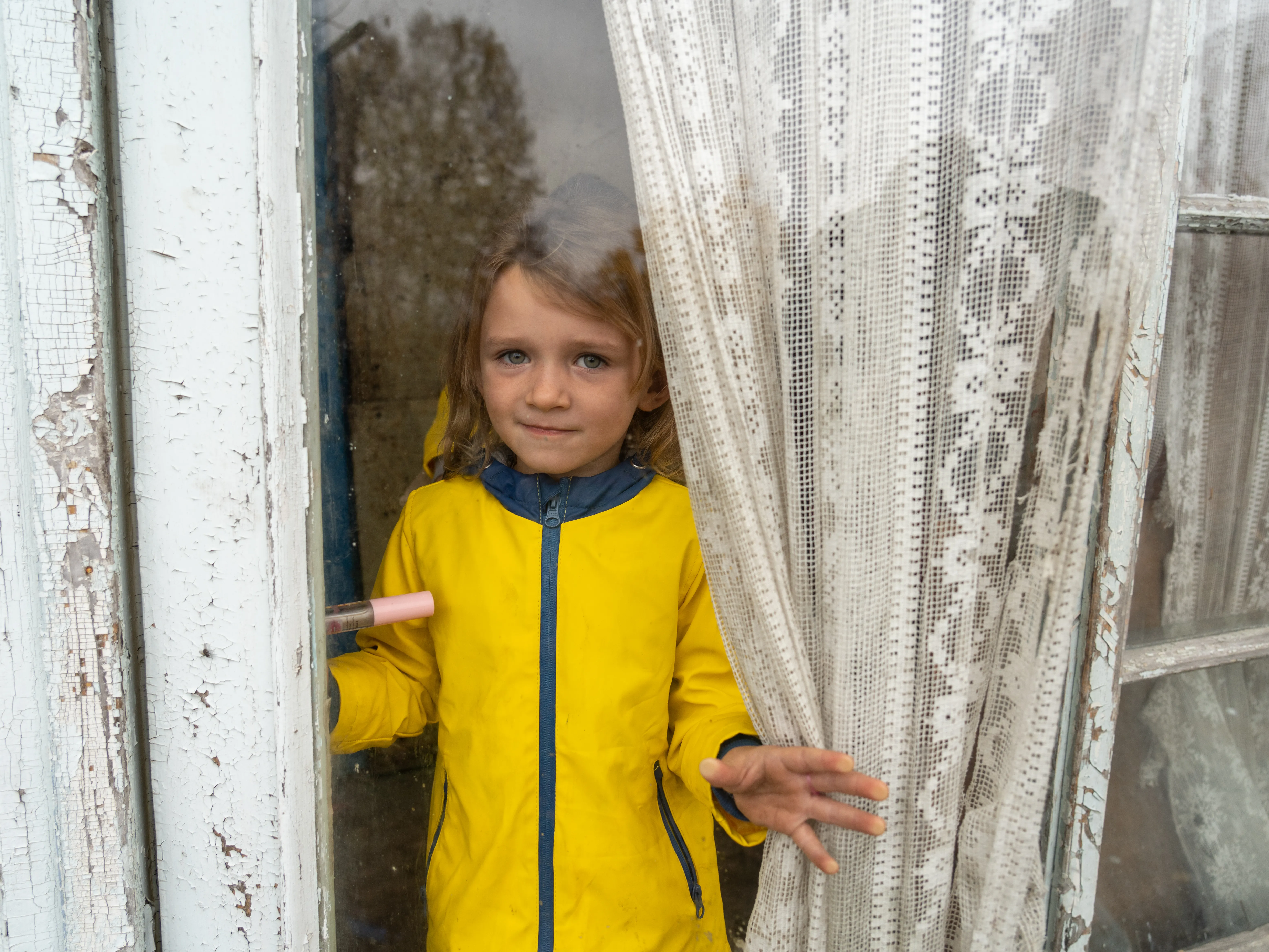 October 29, 2023,  Izium, Kharkivska oblast, Ukraine. Maria (4) is looking through the window of her house.