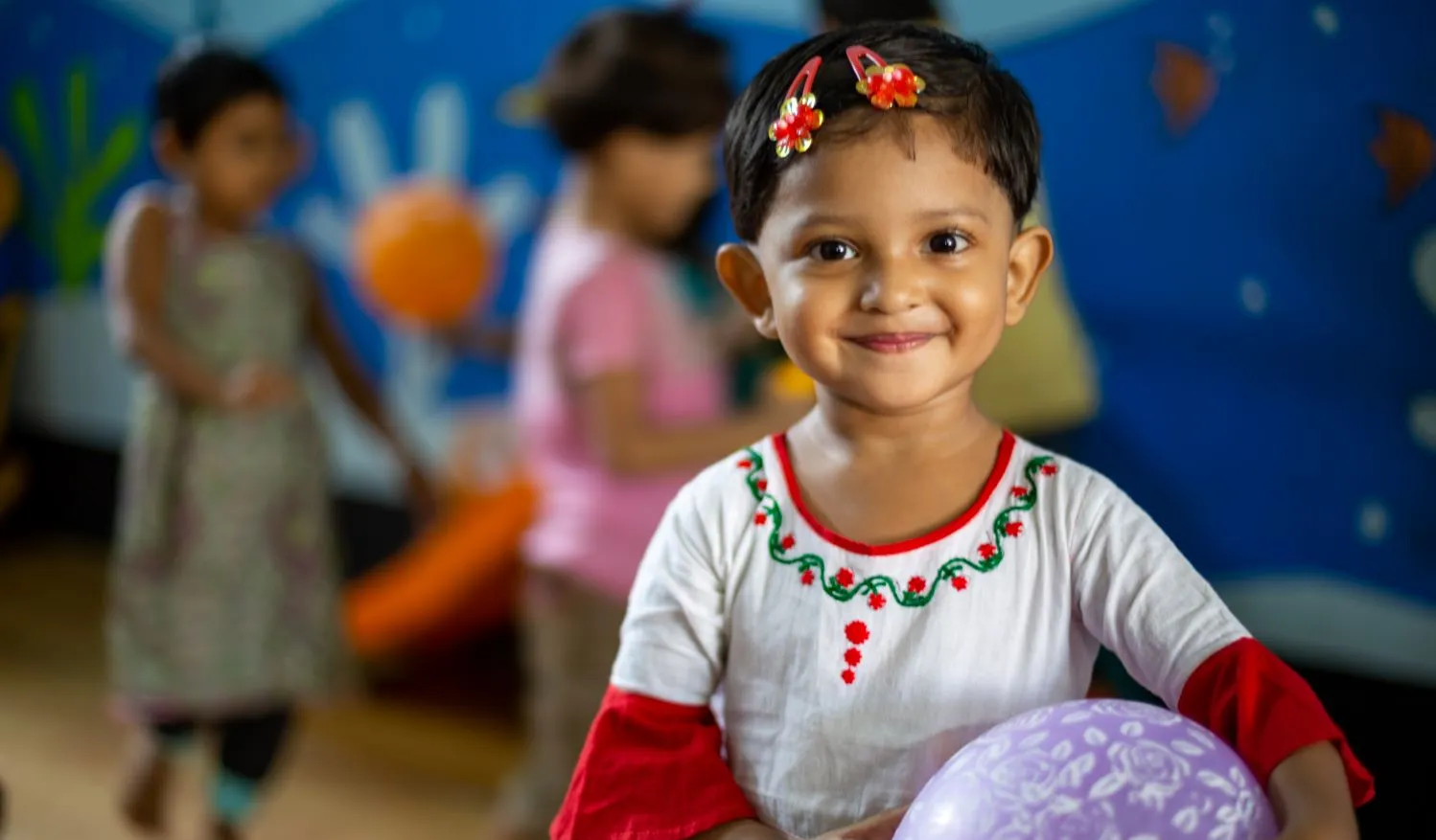 Une jeune fille tient un ballon et sourit pour une photo.