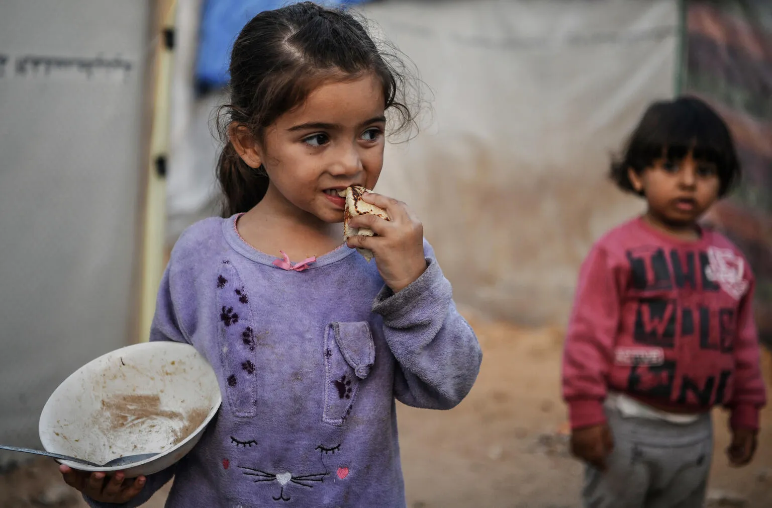 Israa eats a piece of bread in Khan Younis city.