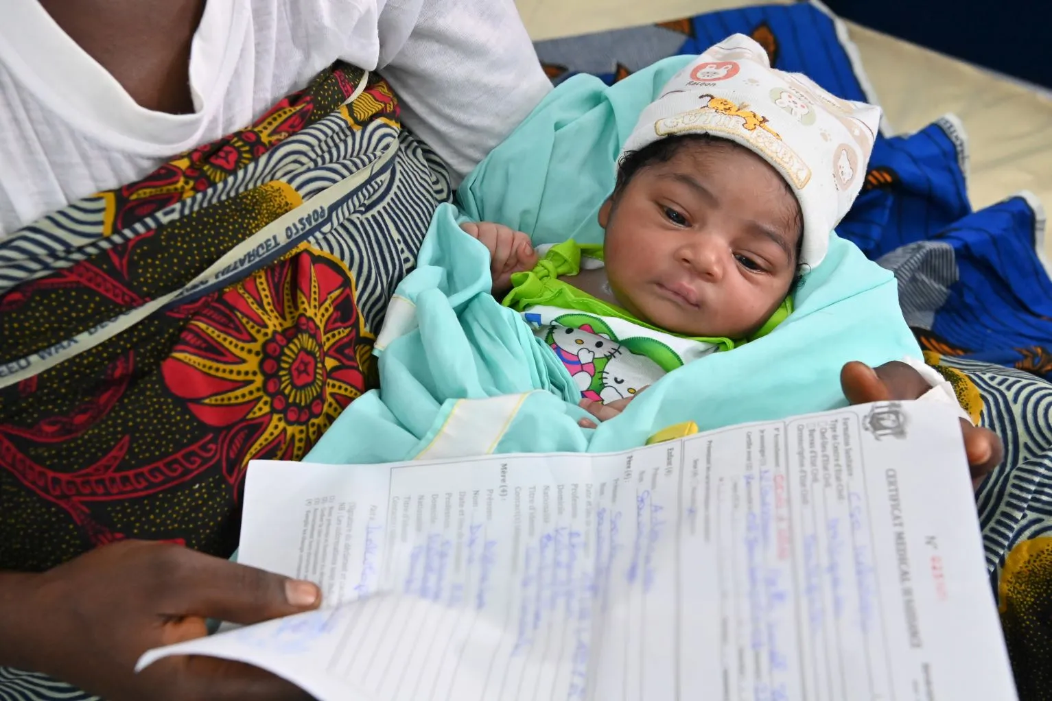 In Côte d'Ivoire, a baby sleeps while her mother holds her birth certificate. 