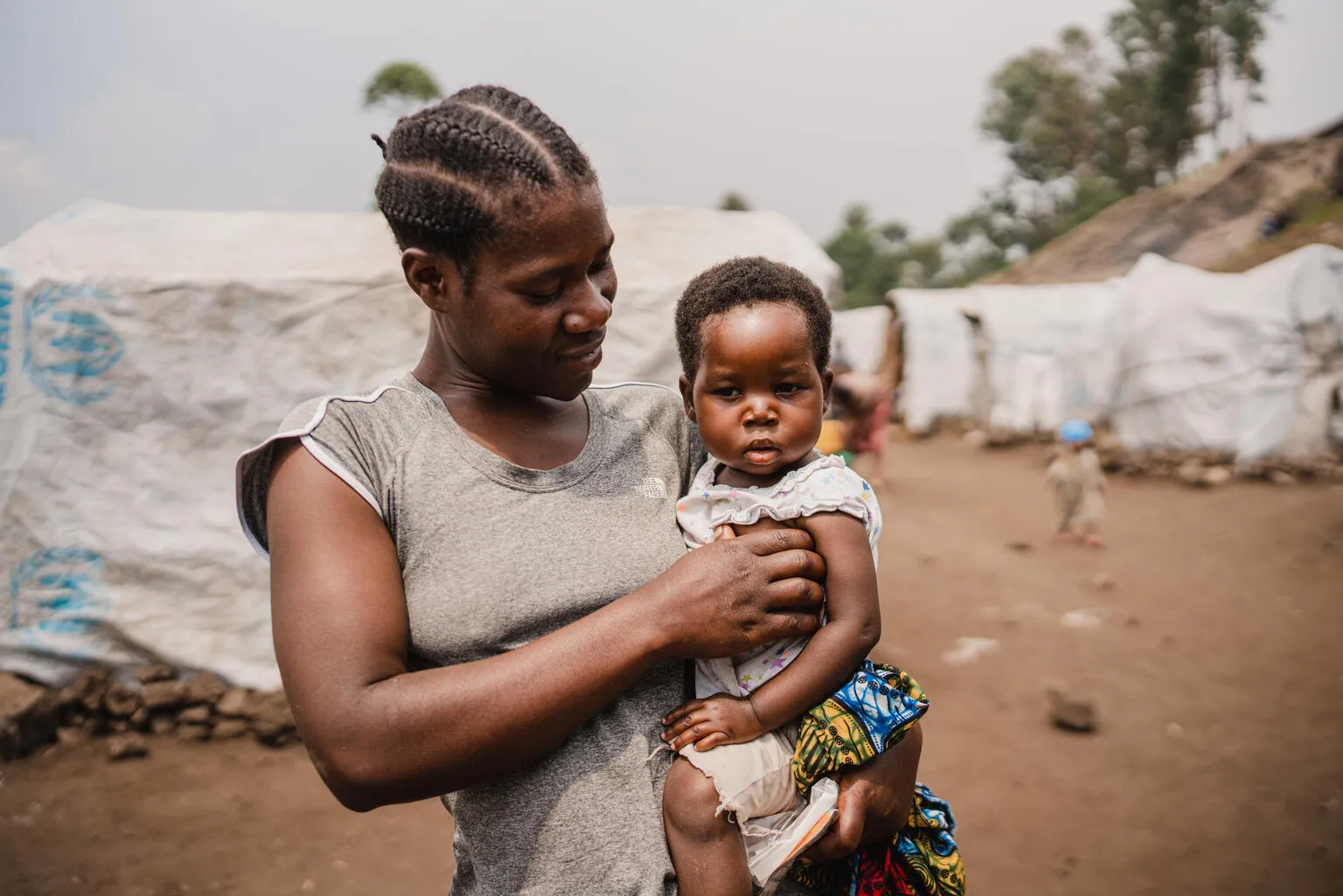 Nehema holds her daughter Queen, aged 2, after the girl's consultation at the mobile clinic set up by UNICEF and the Red Cross at the Lushagala site for displaced people, in North Kivu province, DR Congo, on 20 February 2024.