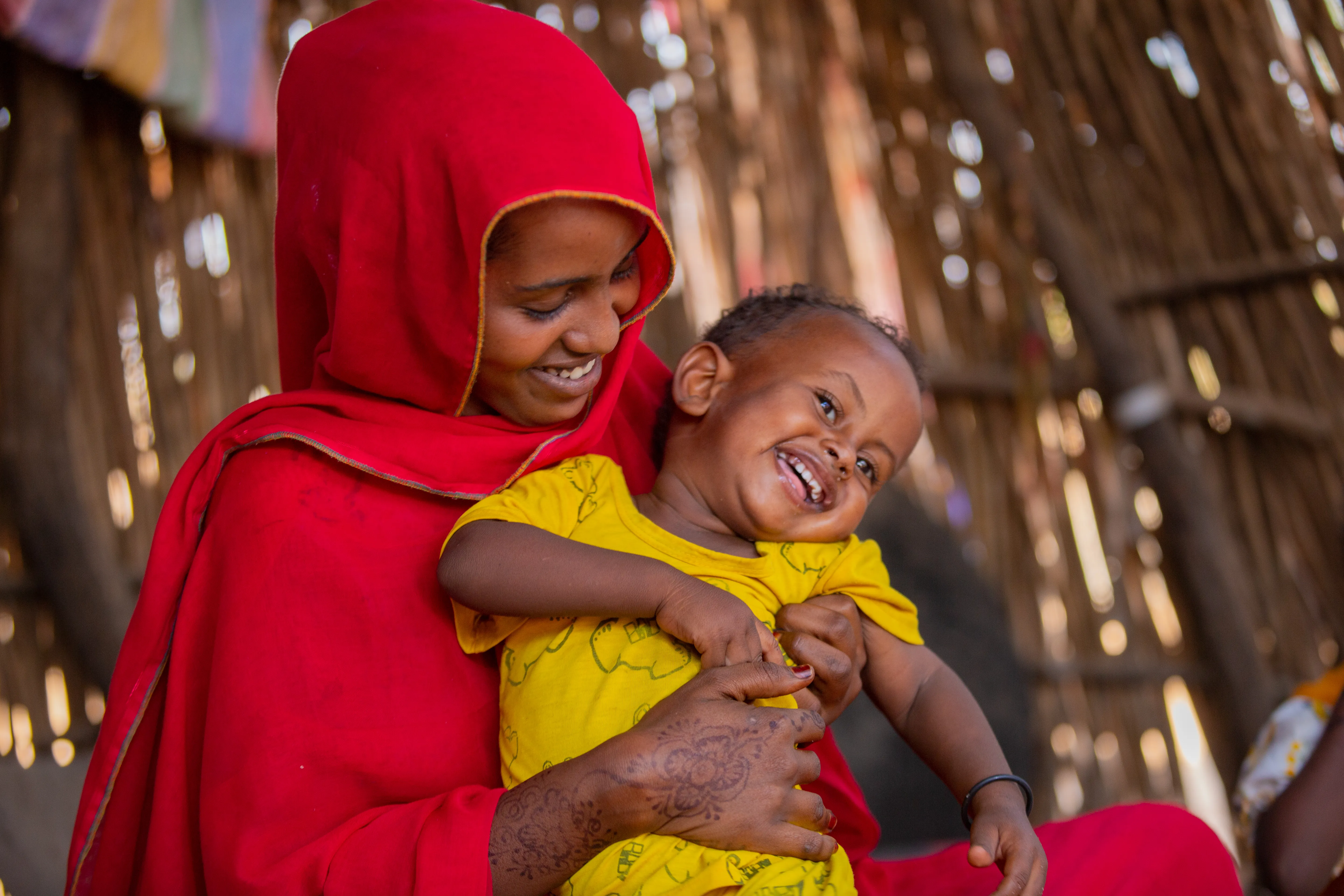 A mother holds her child lovingly as it laughs in her lap. 