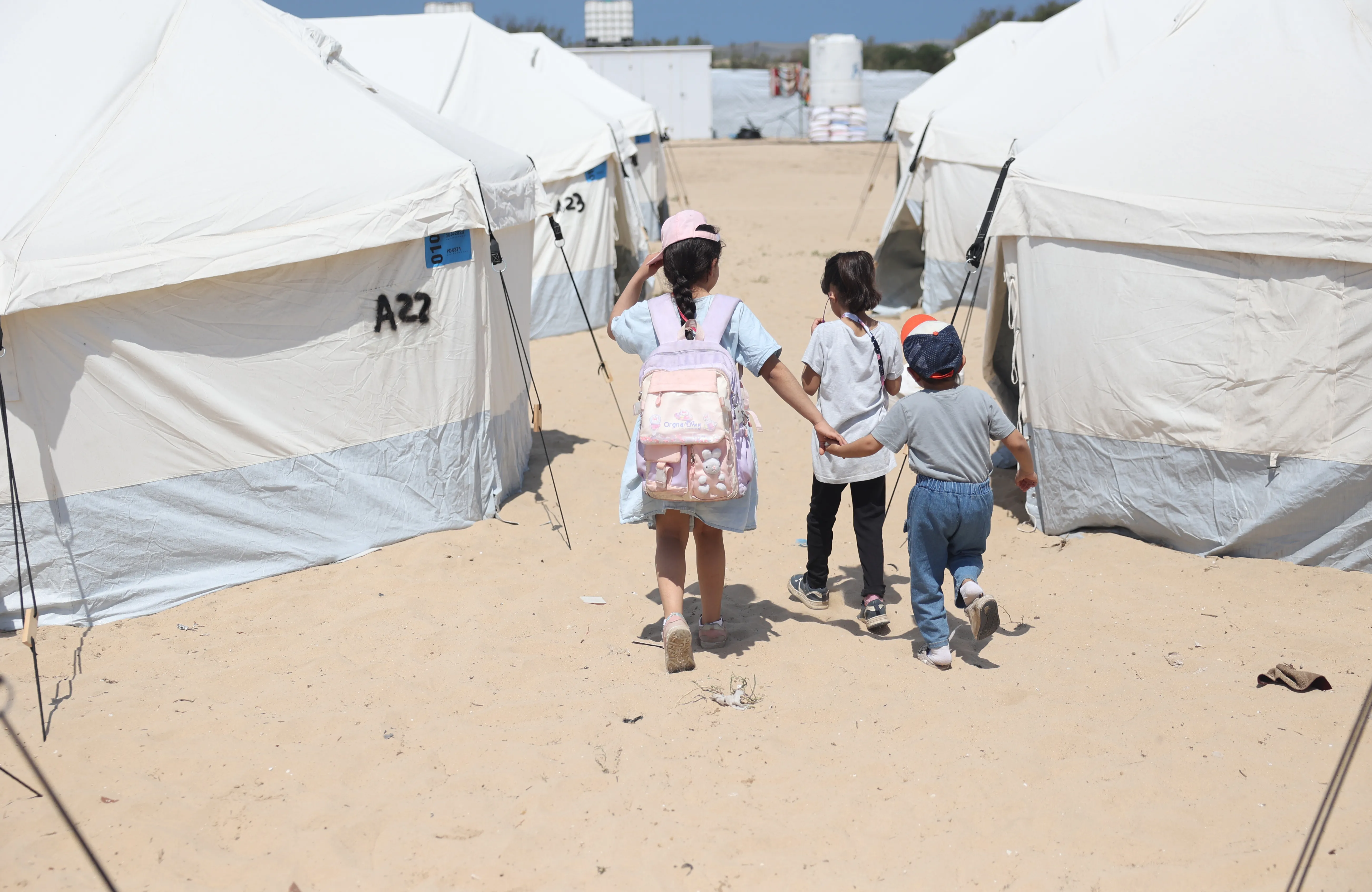 Children walk through the tents in the UK-FCDO supported camp in Rafah, southern the Gaza Strip.