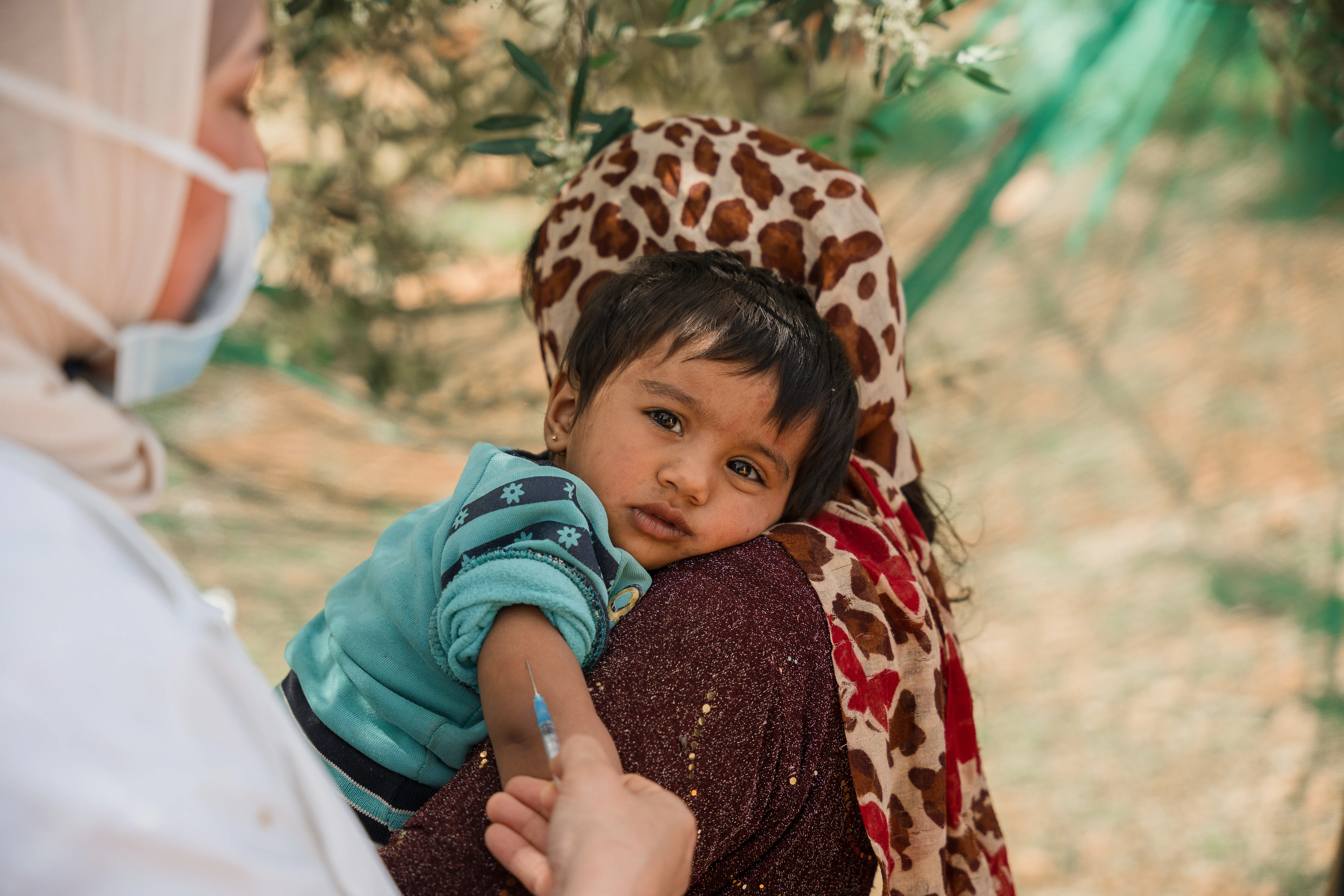 Un jeune enfant regarde pendant qu’il reçoit un vaccin dans un campement informel à Jarish, au nord de la Jordanie, lors d’une campagne de vaccination soutenue par l’UNICEF.