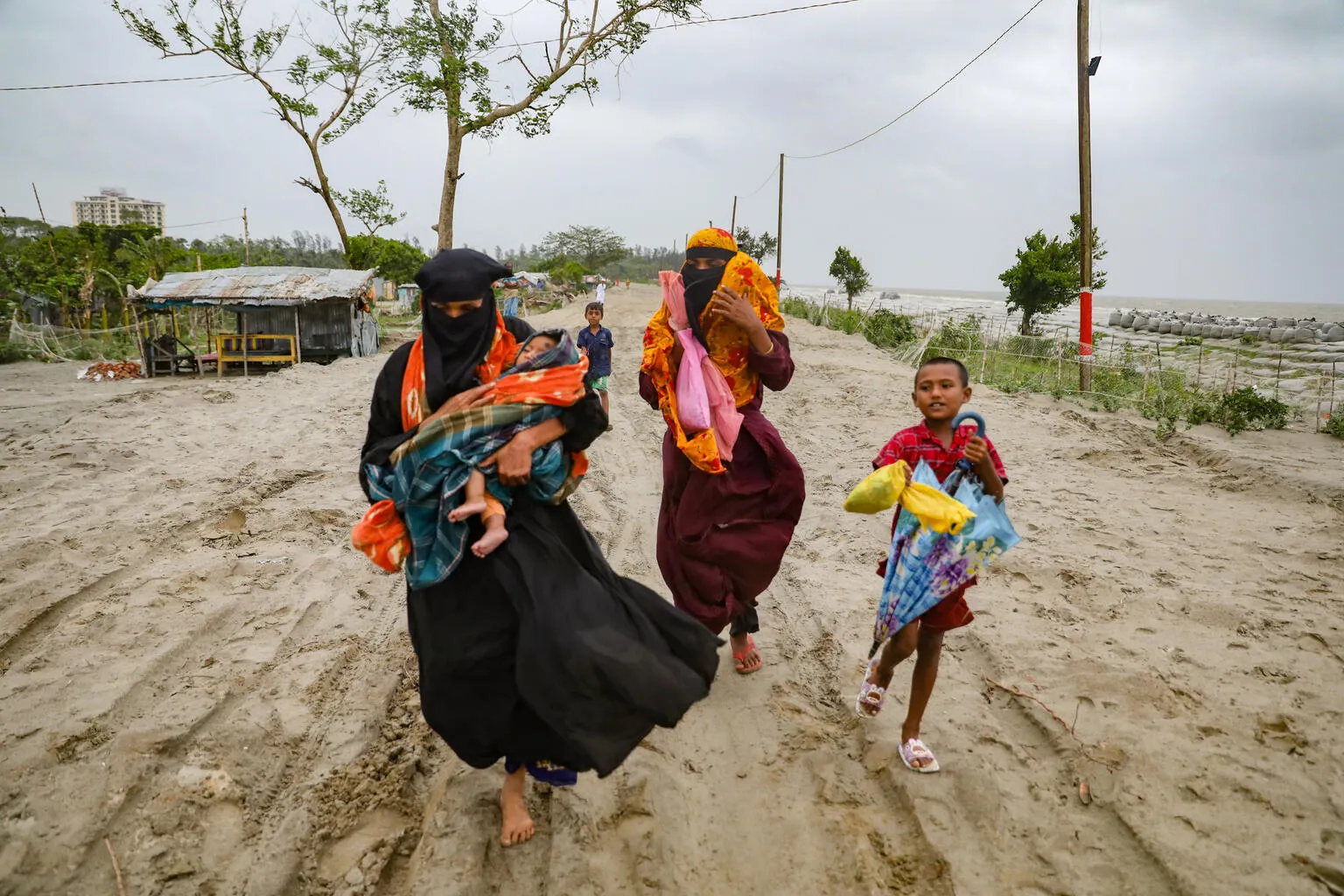 Inhabitants from the village of Panjupara are walking towards the shelter with their children and valuable household items during the rainfall in Kuakata, ahead of cyclone Remal's landfall in Bangladesh on May 26, 2024.