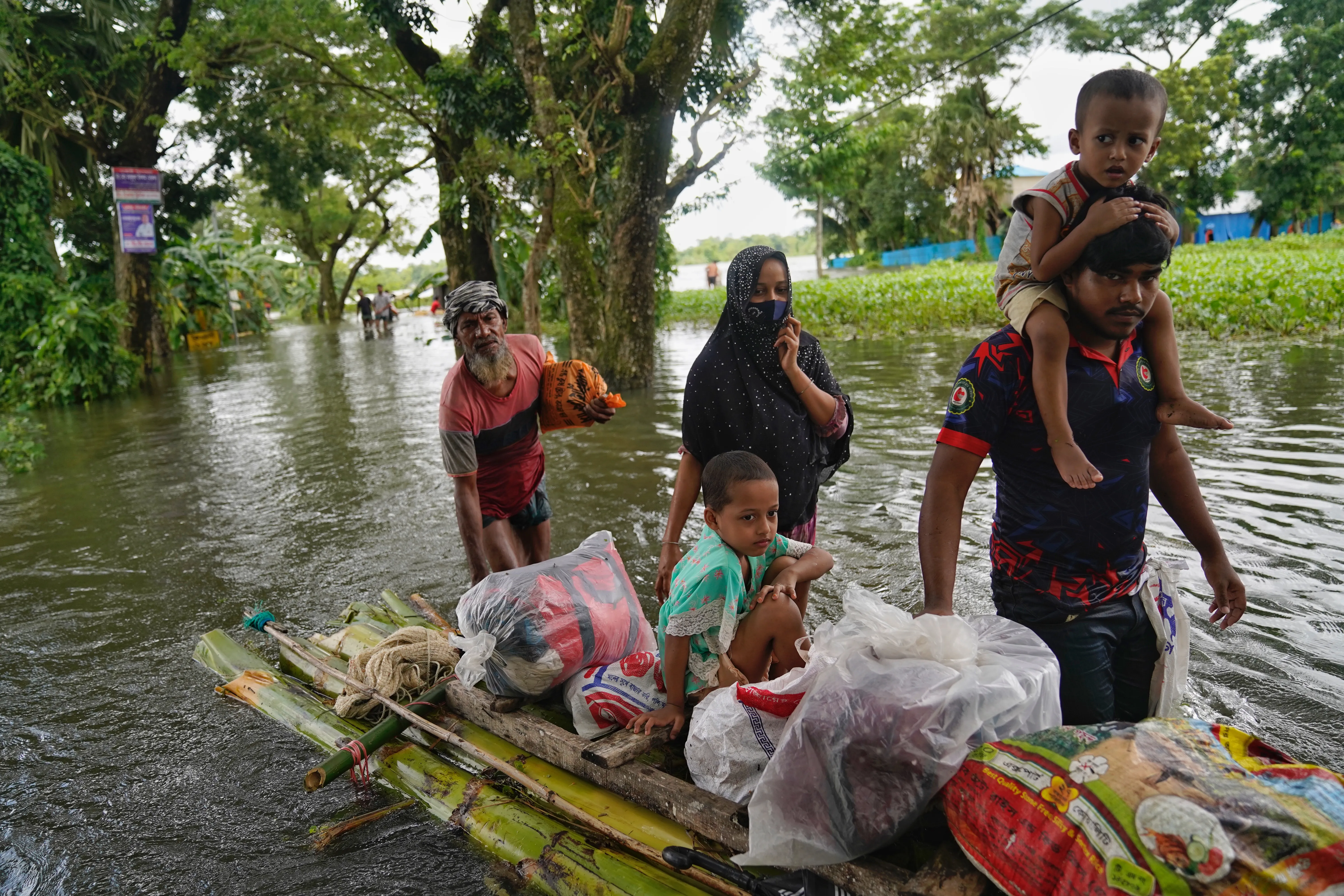 People travelling through the flood water on a make-shift raft, in search of shelter, in Feni.