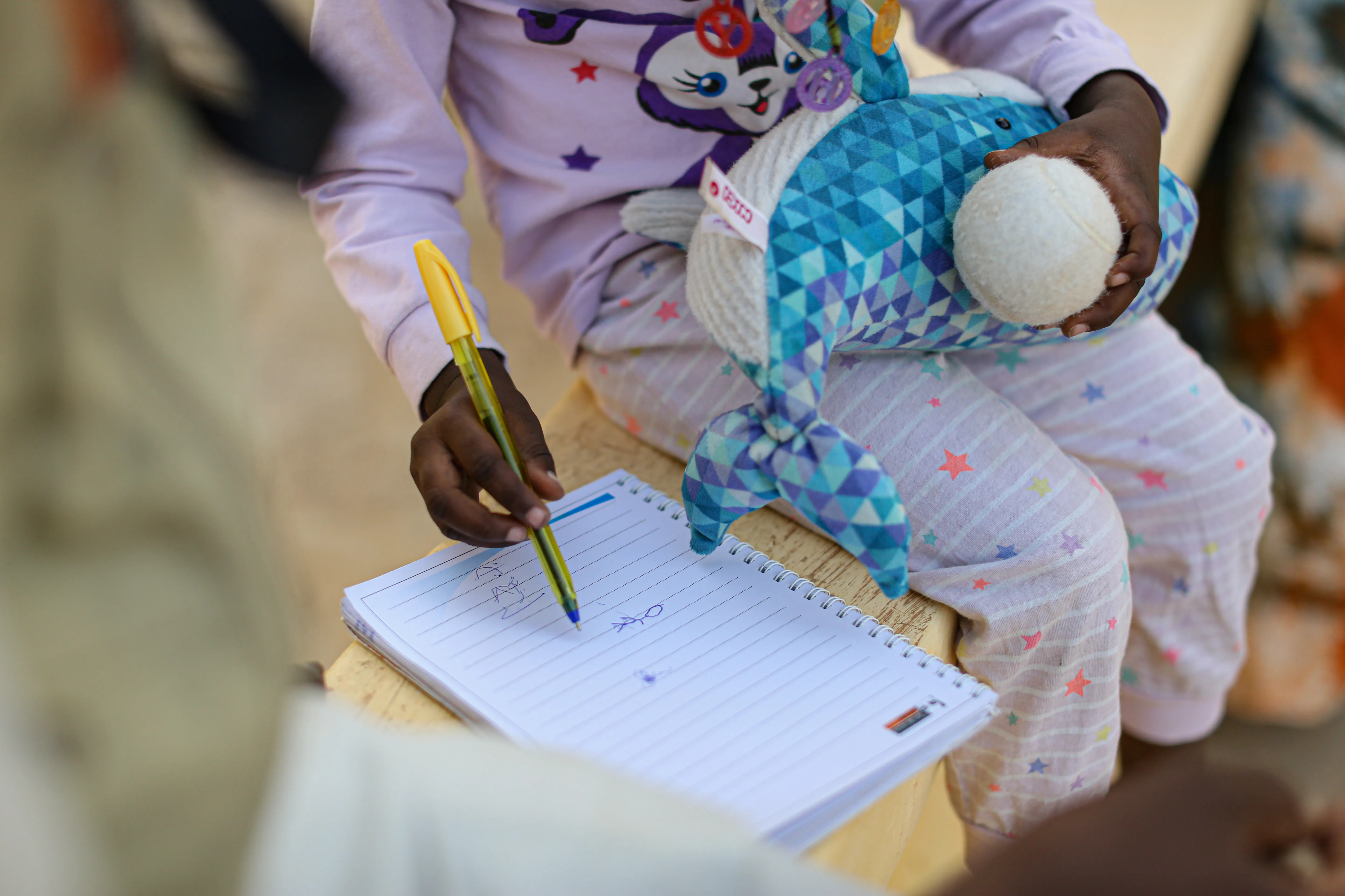 Assourita*, a 5-year-old girl scribbles on a notepad. 