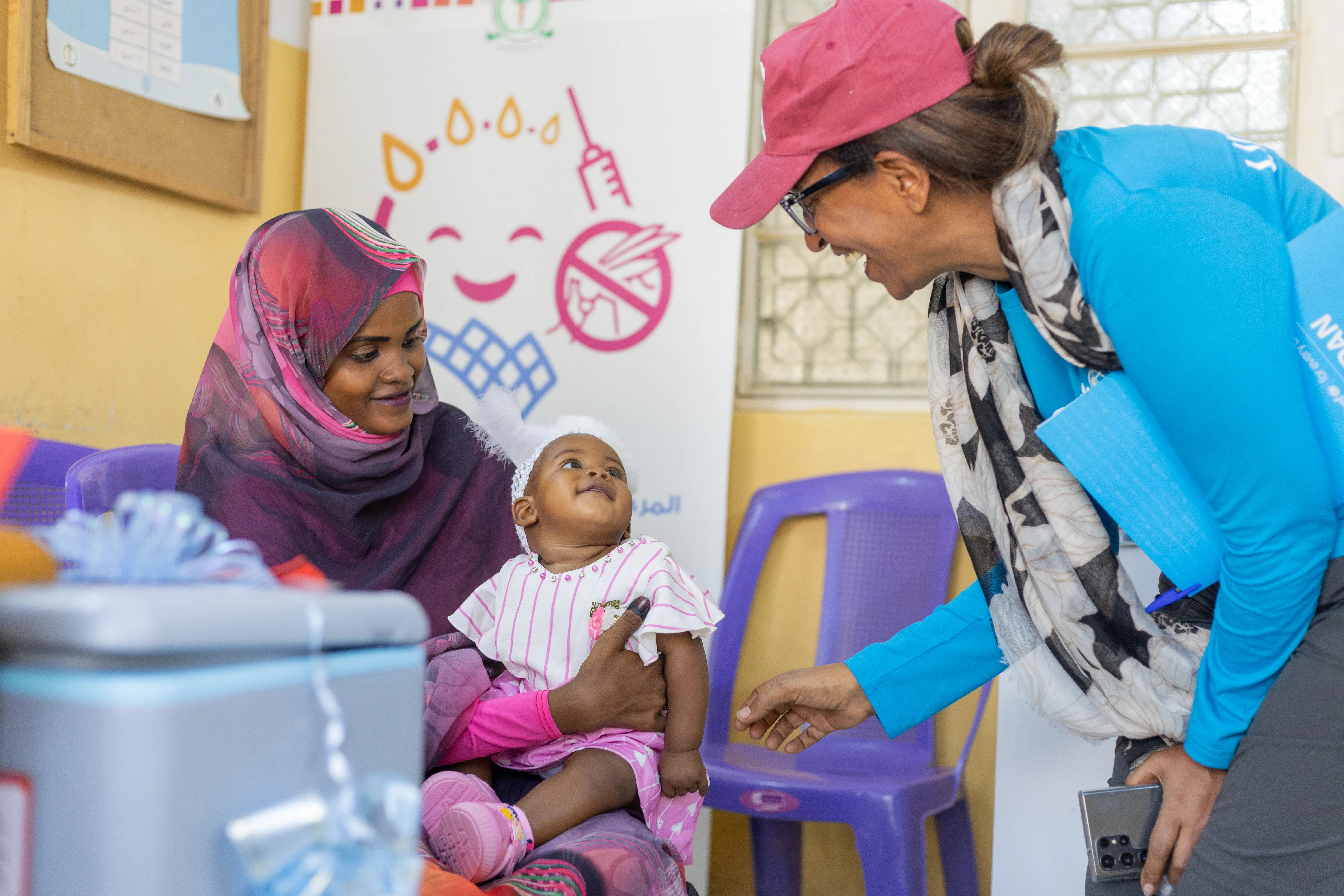 NICEF Sudan’s Chief of Health, shares a light moment with Adan Mohammed, 6 months, before she receives the malaria vaccine. Adan is the very first child to be vaccinated against malaria in Sudan.