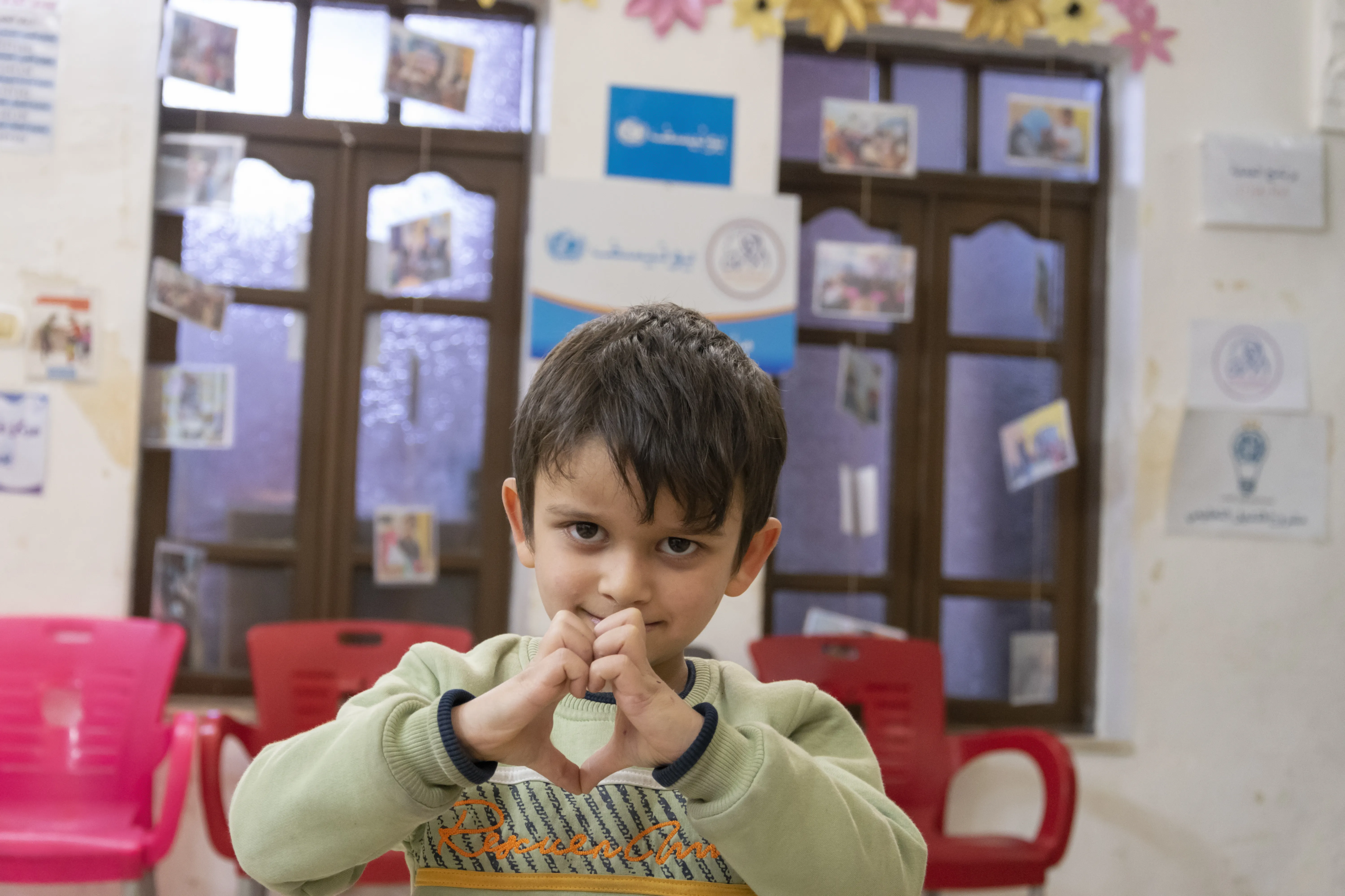 A child makes heart shape with their hands at a child protection centre in Syria 